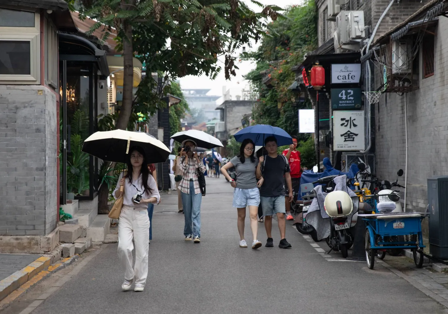 مشاة يسيرون تحت الأمطار في العاصمة الصينية بكين (إ.ب.أ)