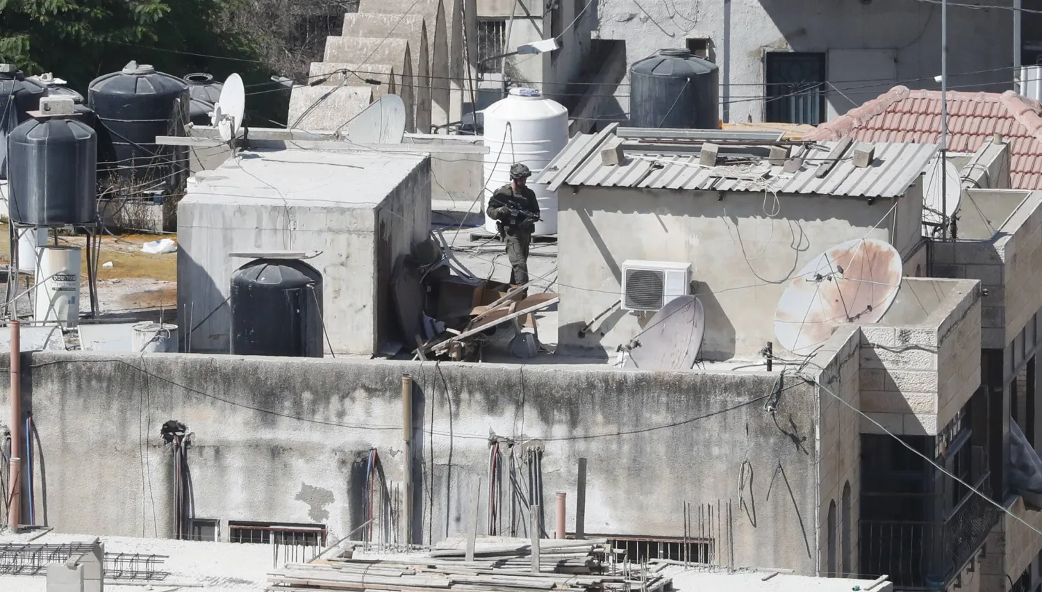 An Israeli soldier searches a roof during a raid in a building amid the ninth day of an ongoing military operation in the West Bank city of Jenin, 05 September 2024. EPA/ALAA BADARNEH