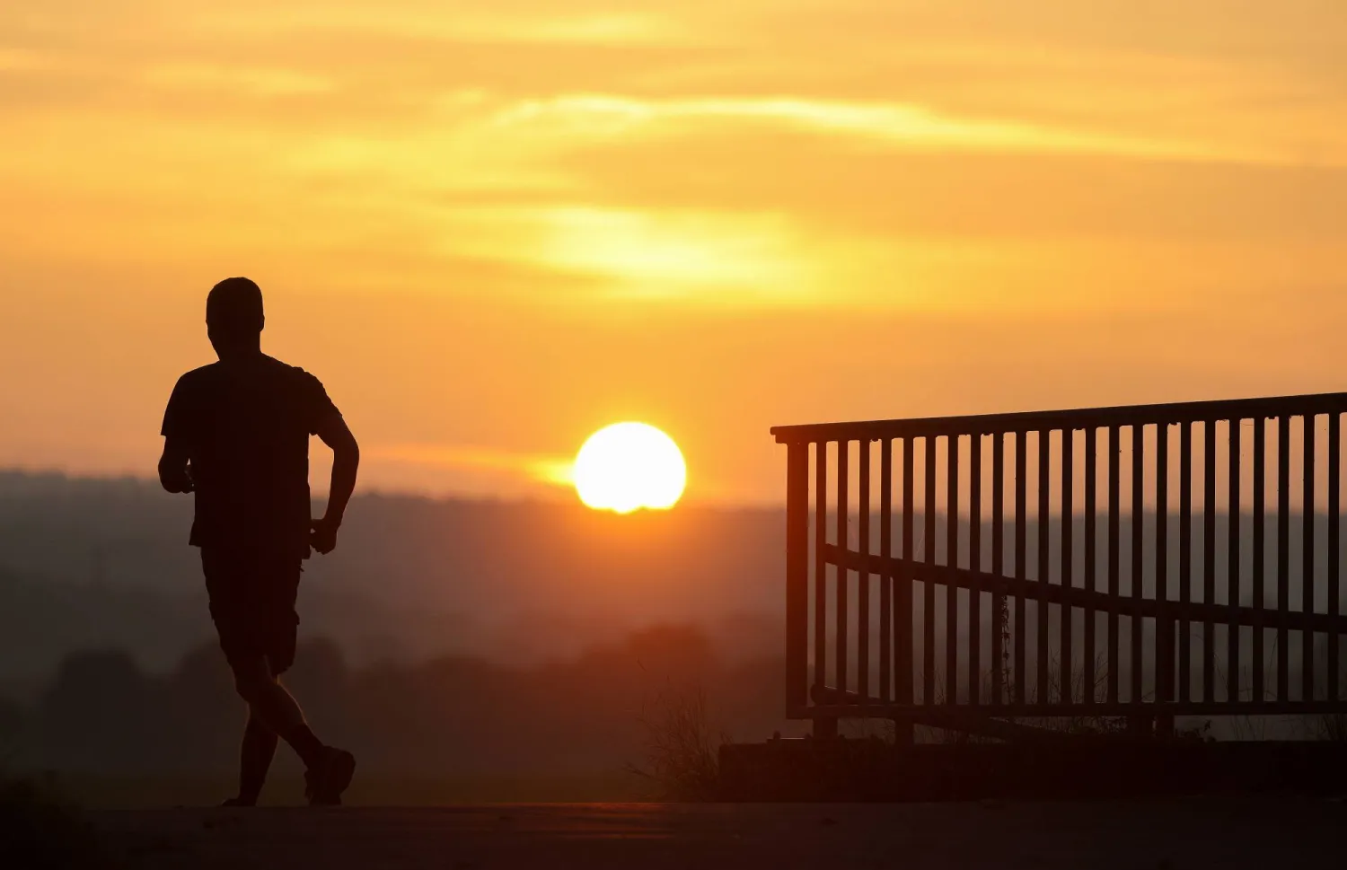 FILED - 05 September 2024, Baden-Württemberg, Seekirch: A jogger is out and about in the morning while the sun rises in the background. Photo: Thomas Warnack/dpa