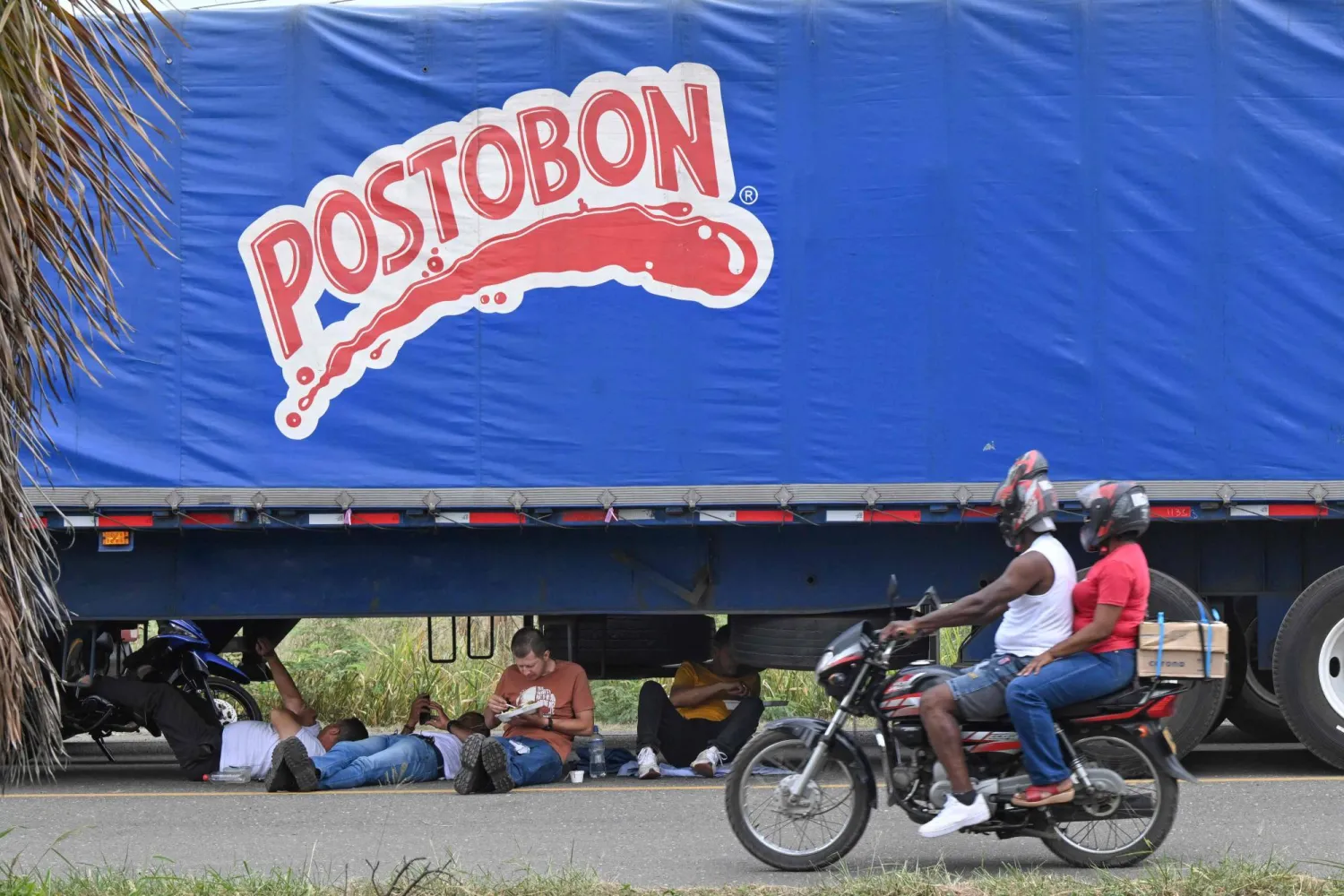 Truckers eat their lunch while blocking a street during a protest against the diesel price increase in Cali, Colombia, on September 5, 2024. (Photo by JOAQUIN SARMIENTO / AFP)
