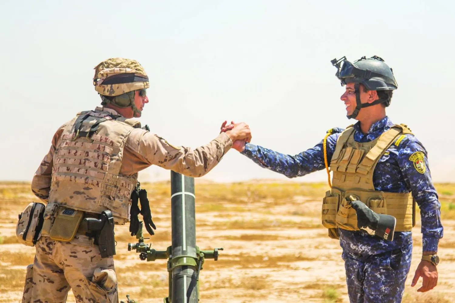 Uluslararası Koalisyon’un askeri eğitmeni, eğitim kampında Iraklı bir askerle tokalaşıyor. (CENTCOM)