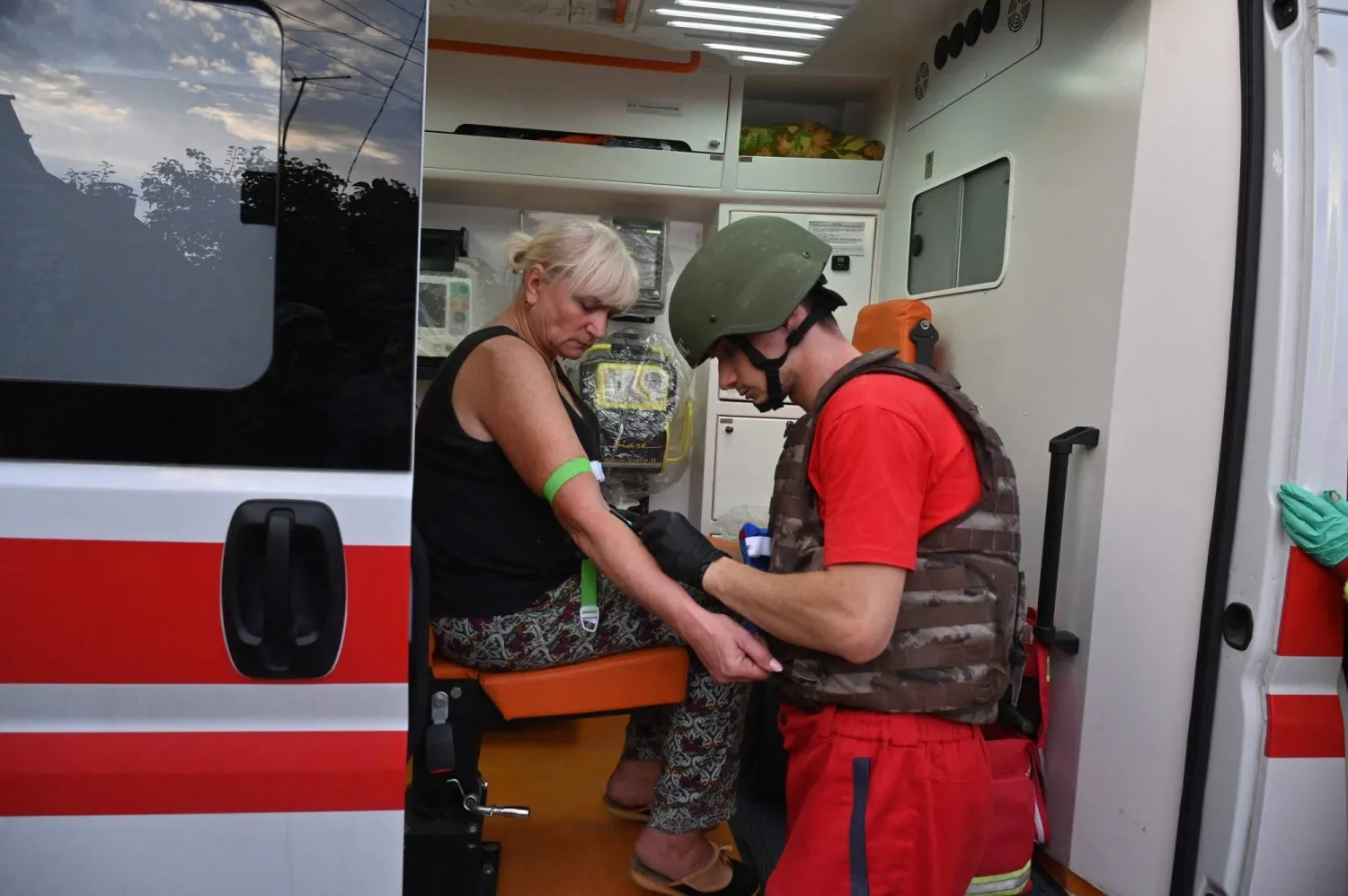 Rusya'nın Harkiv bölgesindeki küçük bir kasabaya düzenlediği saldırıda yaralanan kadına ilk yardım yapılıyor (AFP)