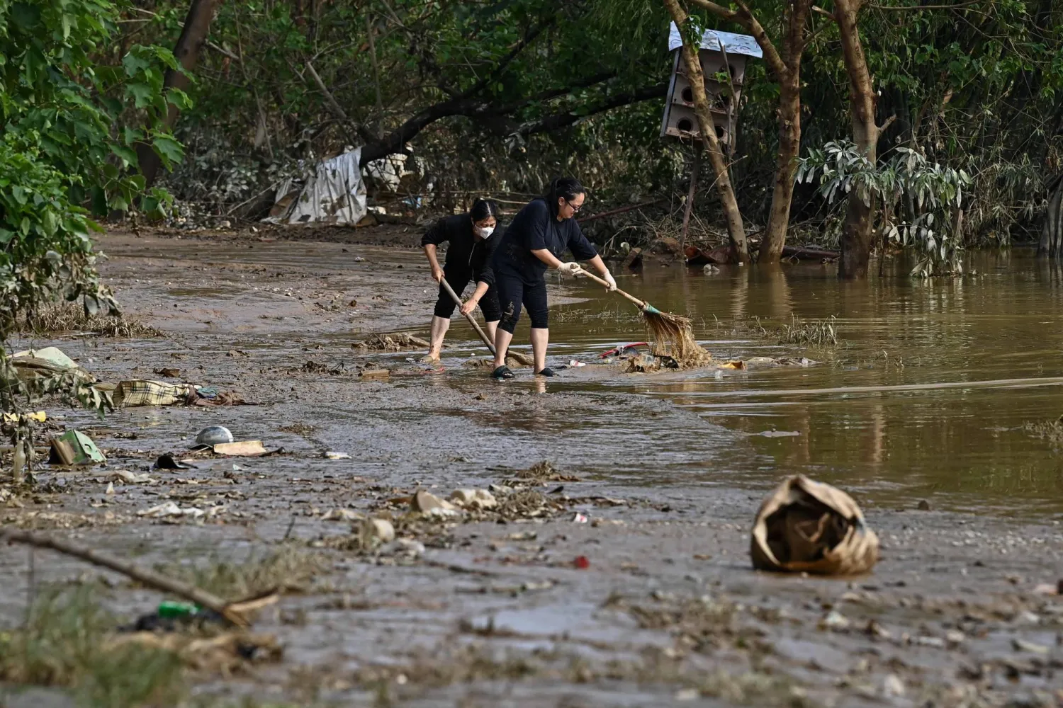 Residents clean up after flood waters receded in Hanoi on September 13, 2024. (Photo by NHAC NGUYEN / AFP)
