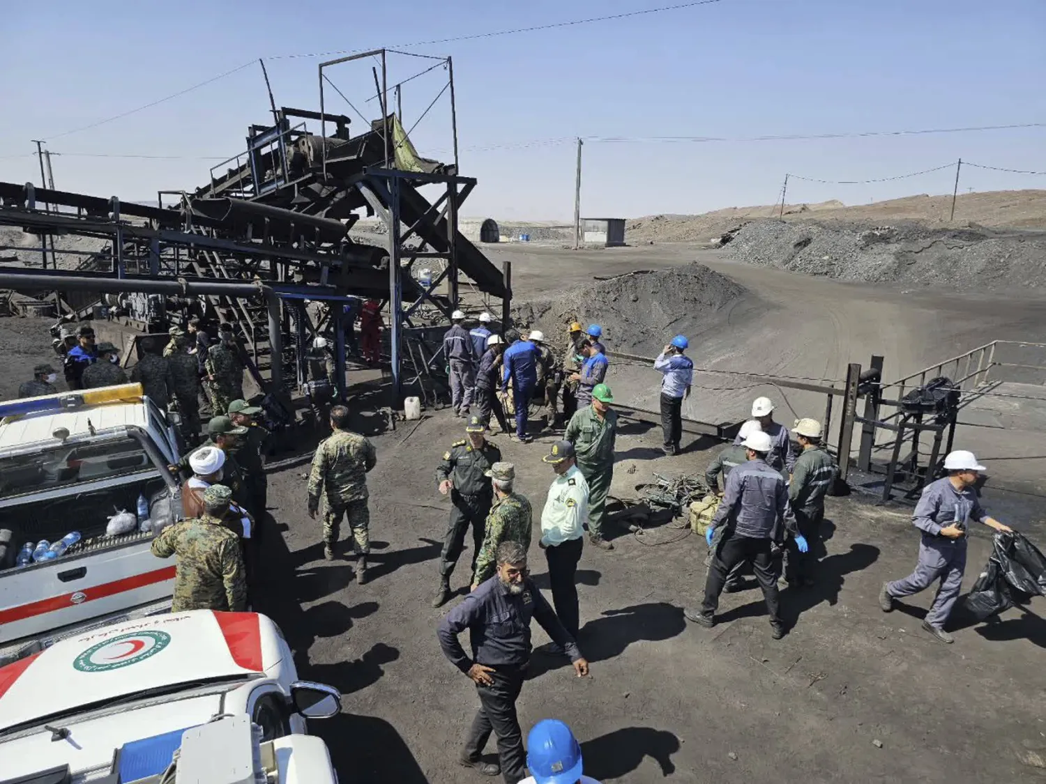 In this photo released by Iranian Red Crescent Society, miners and police officers are seen at the site of a coal mine where methane leak sparked an explosion on Saturday, in Tabas, Iran, Sunday, Sept. 22, 2024. (Iranian Red Crescent Society, via AP)