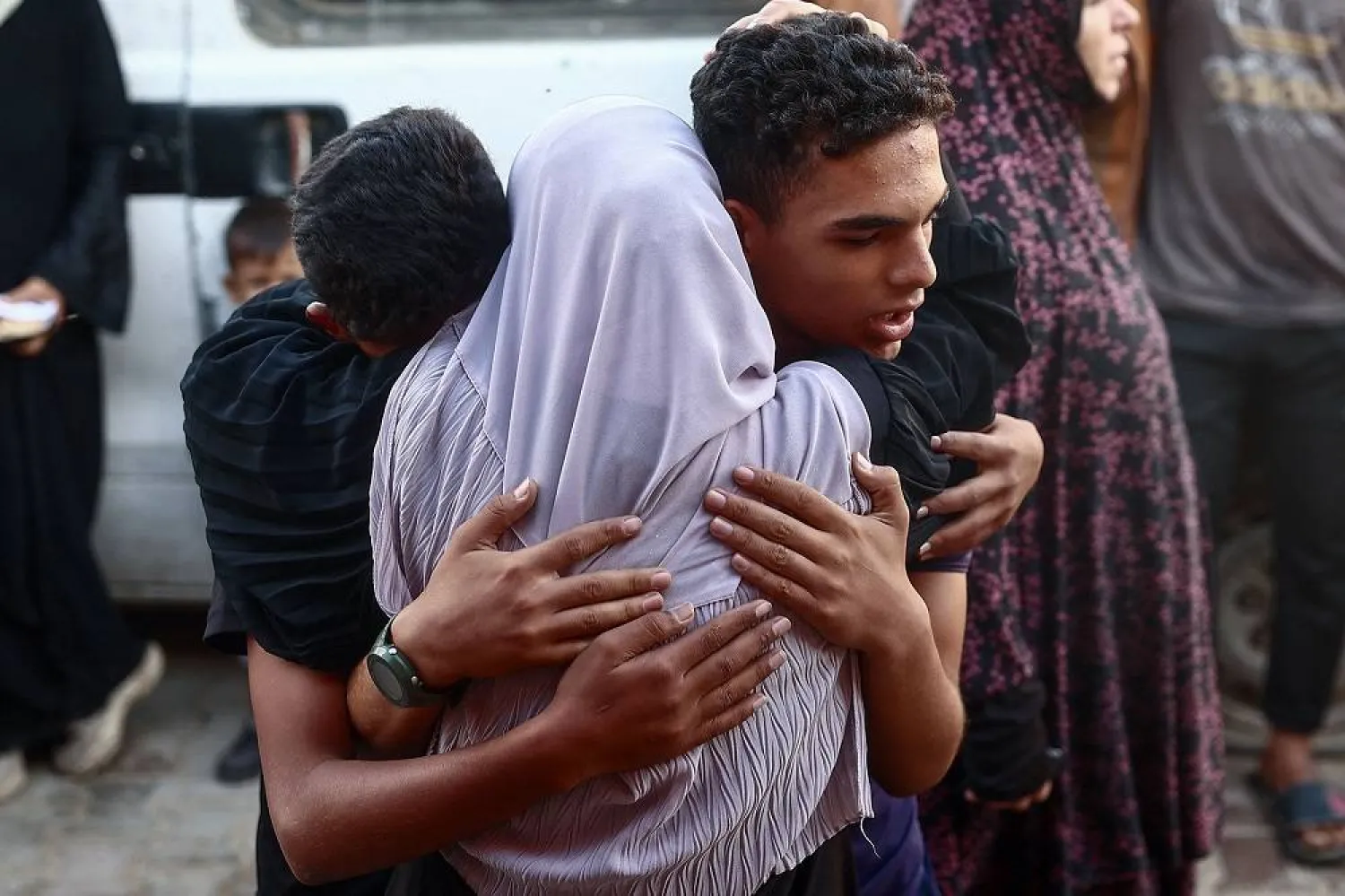 Palestinian youths hug a woman outside a hospital morgue in Deir al-Balah in the central Gaza Strip after an Israeli air strike hit a school sheltering displaced people killing several, on September 23, 2024, amid the ongoing war in the Palestinian territory between Israel and Hamas. (AFP) 