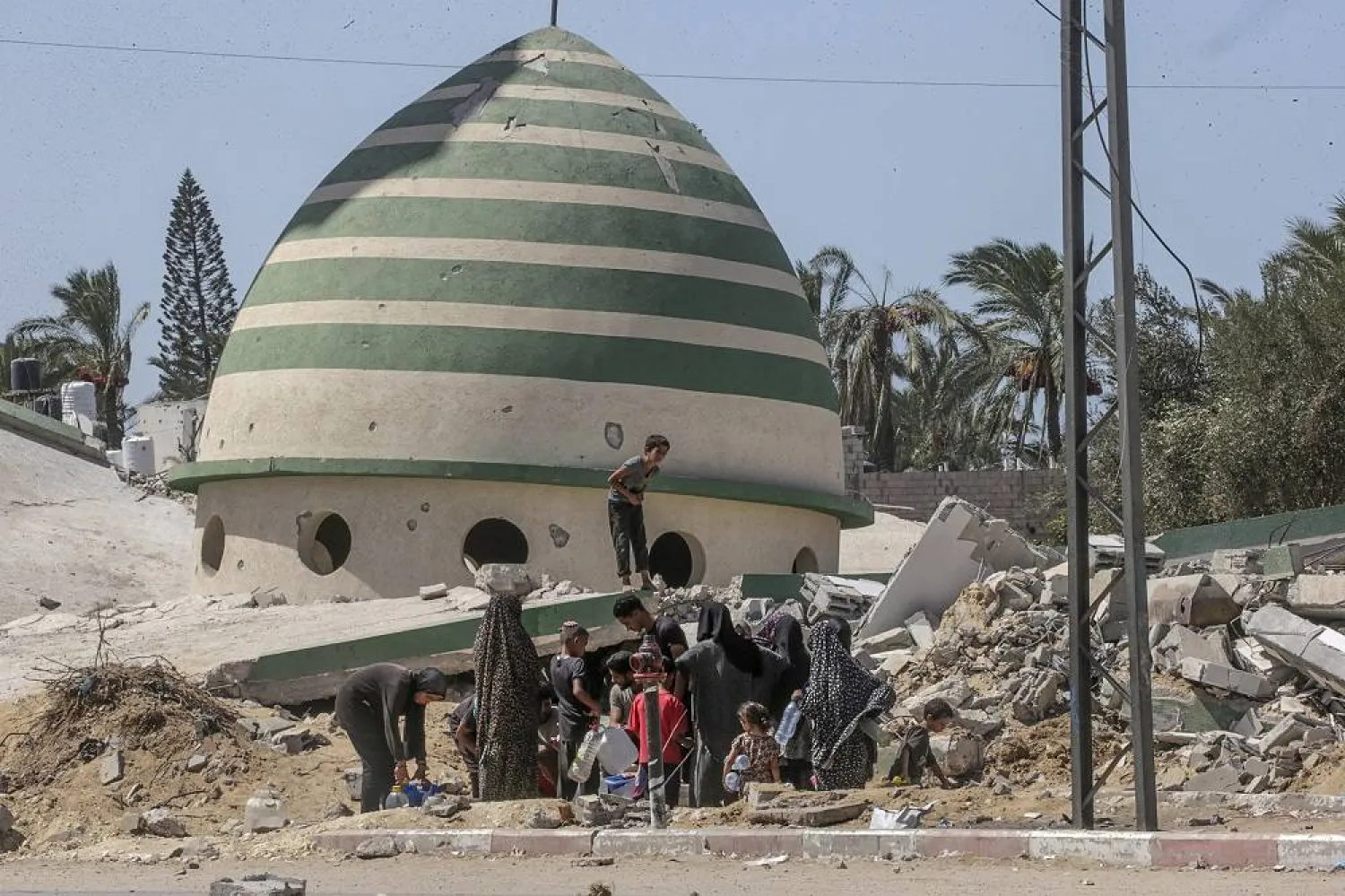 Internally displaced Palestinians wait to fill water near destroyed buildings in Deir al-Balah, central Gaza Strip, 19 September 2024. (EPA) 