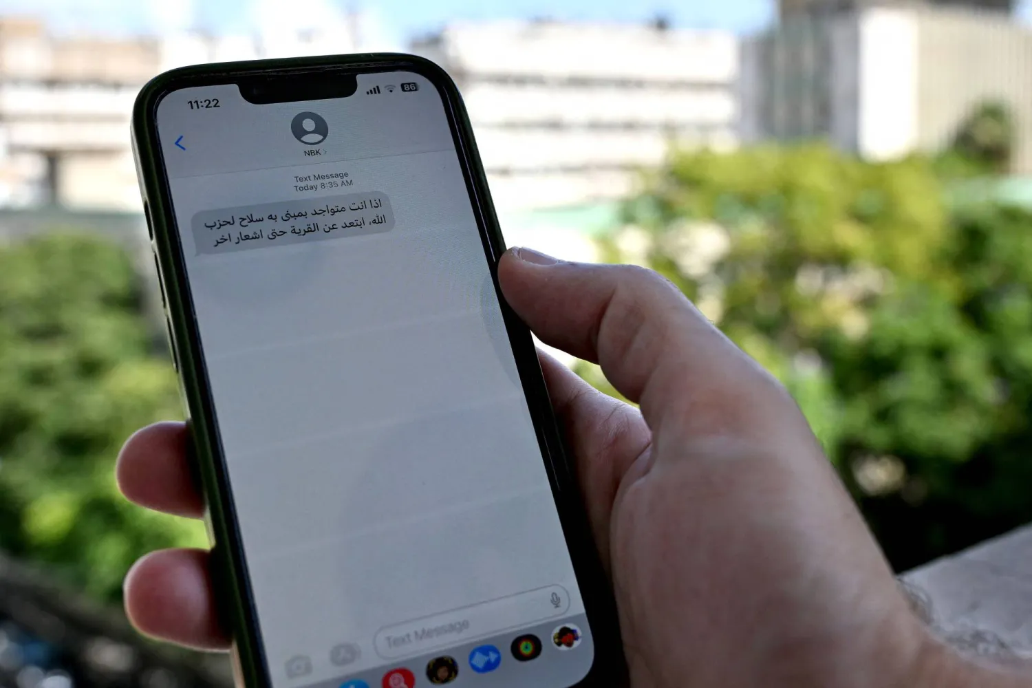 لبناني يمسك هاتفه وعليه رسالة من الجيش الإسرائيلي للإخلاء (أ.ف.ب)