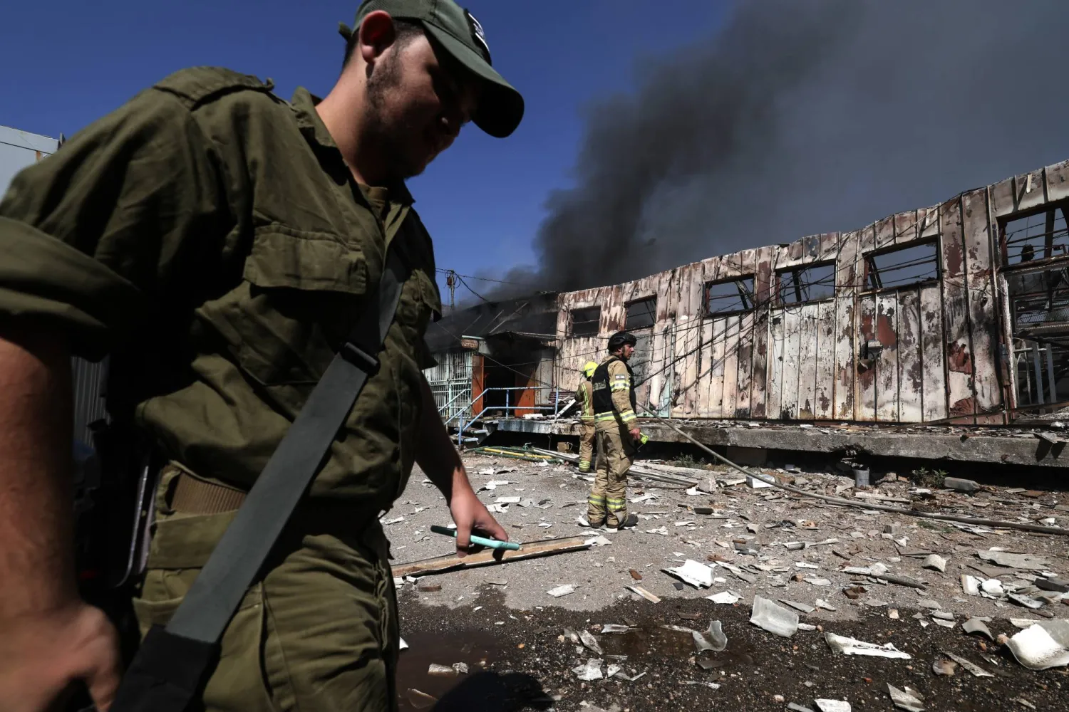 رجال الإطفاء يخمدون حريقاً بعد سقوط مقذوفات أطلقت من لبنان على مخزن للطوارئ في كريات شمونة شمال إسرائيل (إ.ب.أ)