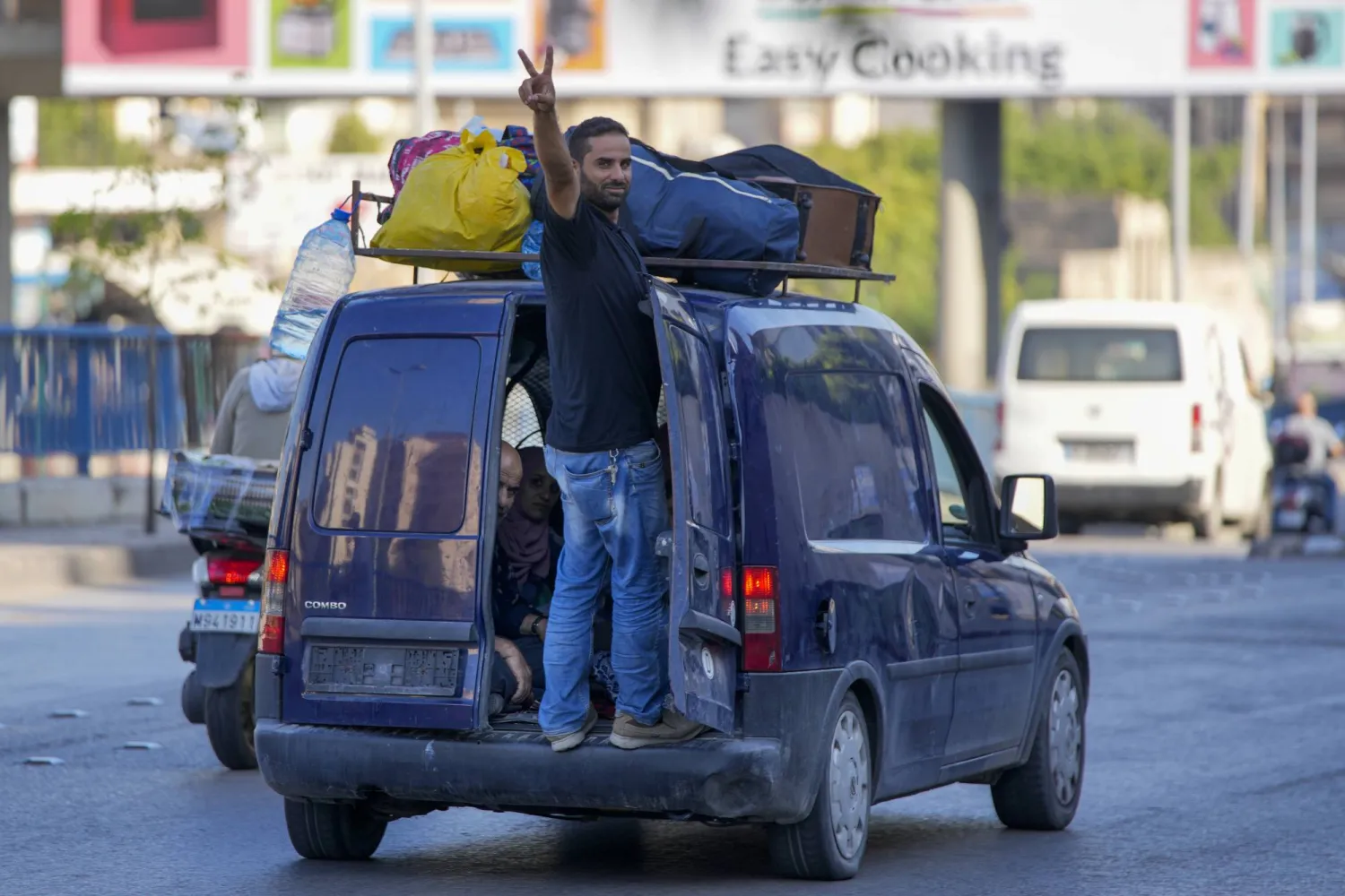 لبناني يرفع شارة النصر خلال نزوحه من الجنوب إلى مكان أكثر أماناً (أ.ب)
