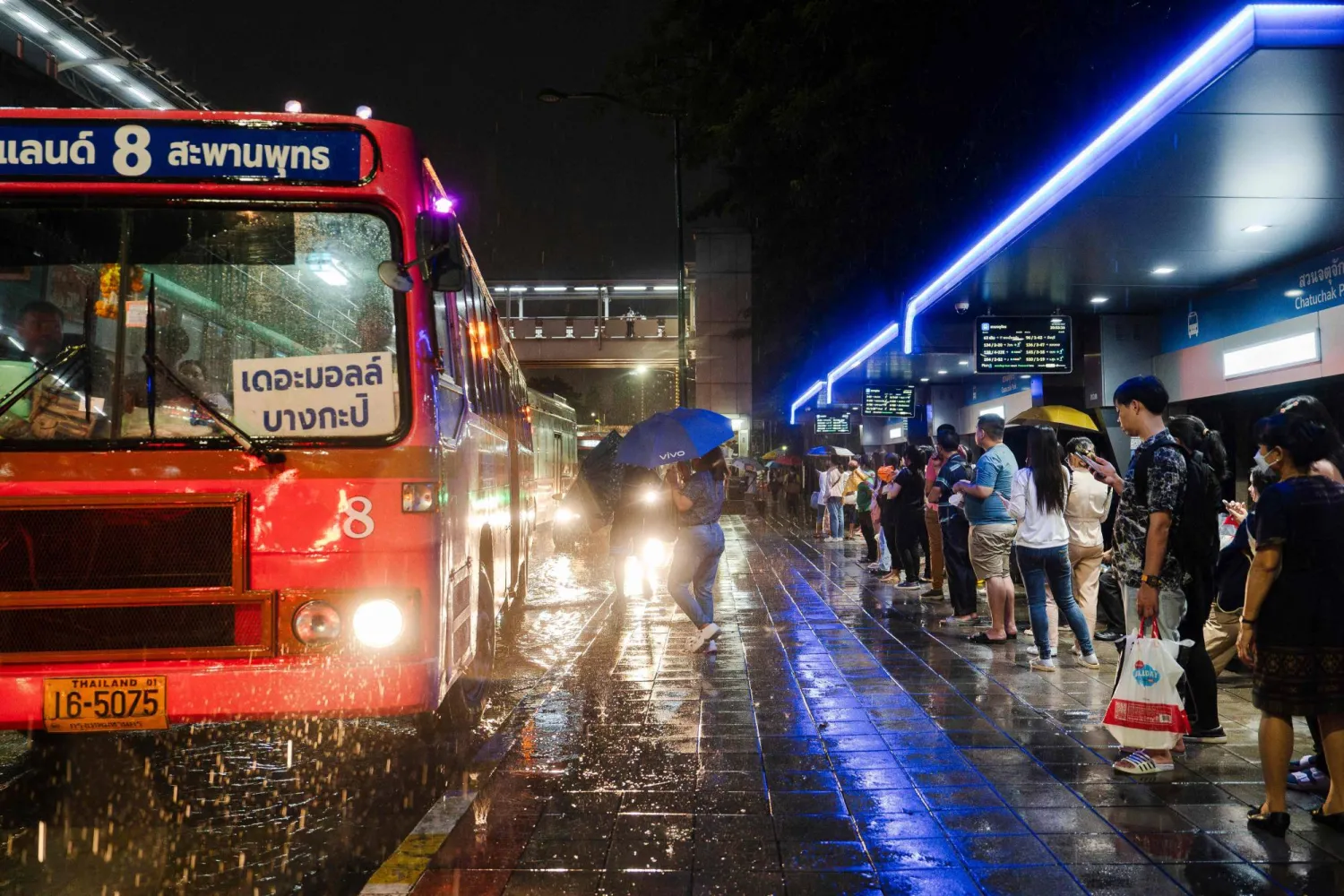 Commuters wait at a bus stop during heavy rain in Bangkok on September 24, 2024. (Photo by Chanakarn Laosarakham / AFP)