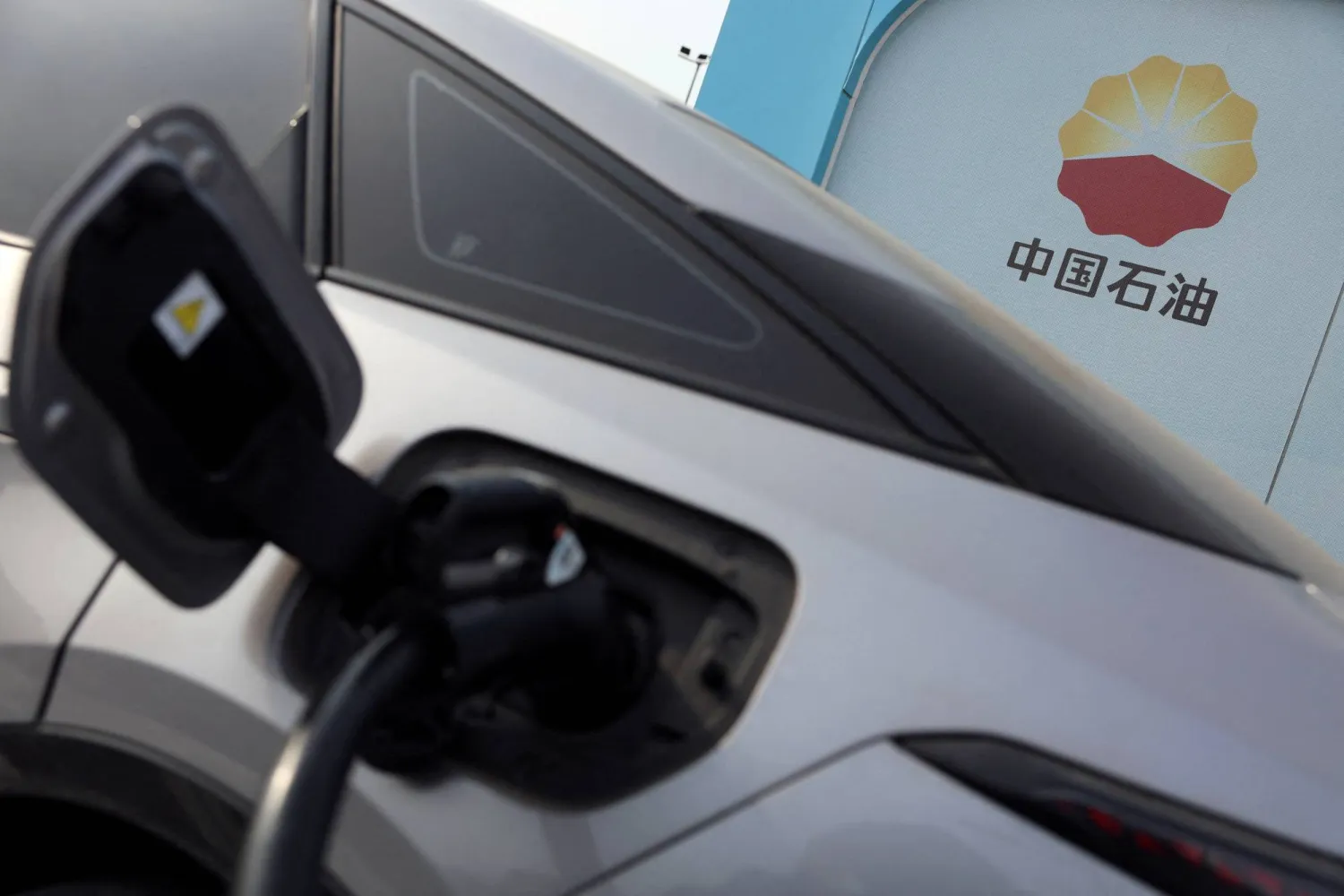 FILE PHOTO: The PetroChina logo is seen near a car charging at the Chinese state oil giant's electric vehicle (EV) charging station in Beijing, China February 2, 2024. REUTERS/Florence Lo/File Photo