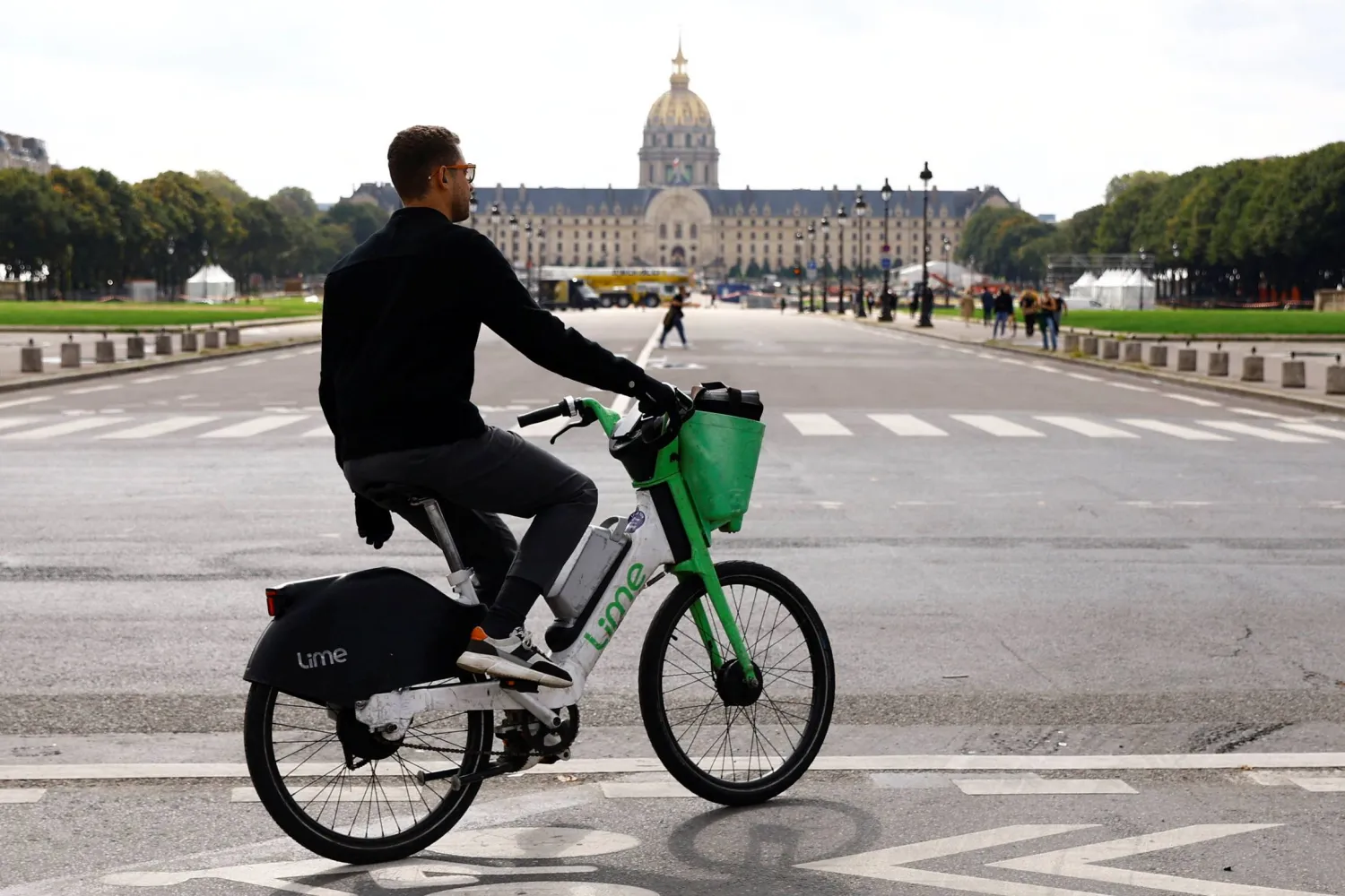 A man rides an electric Lime bicycle on a bike path past the Hotel des Invalides in Paris, France, September 23, 2024. REUTERS/Abdul Saboor