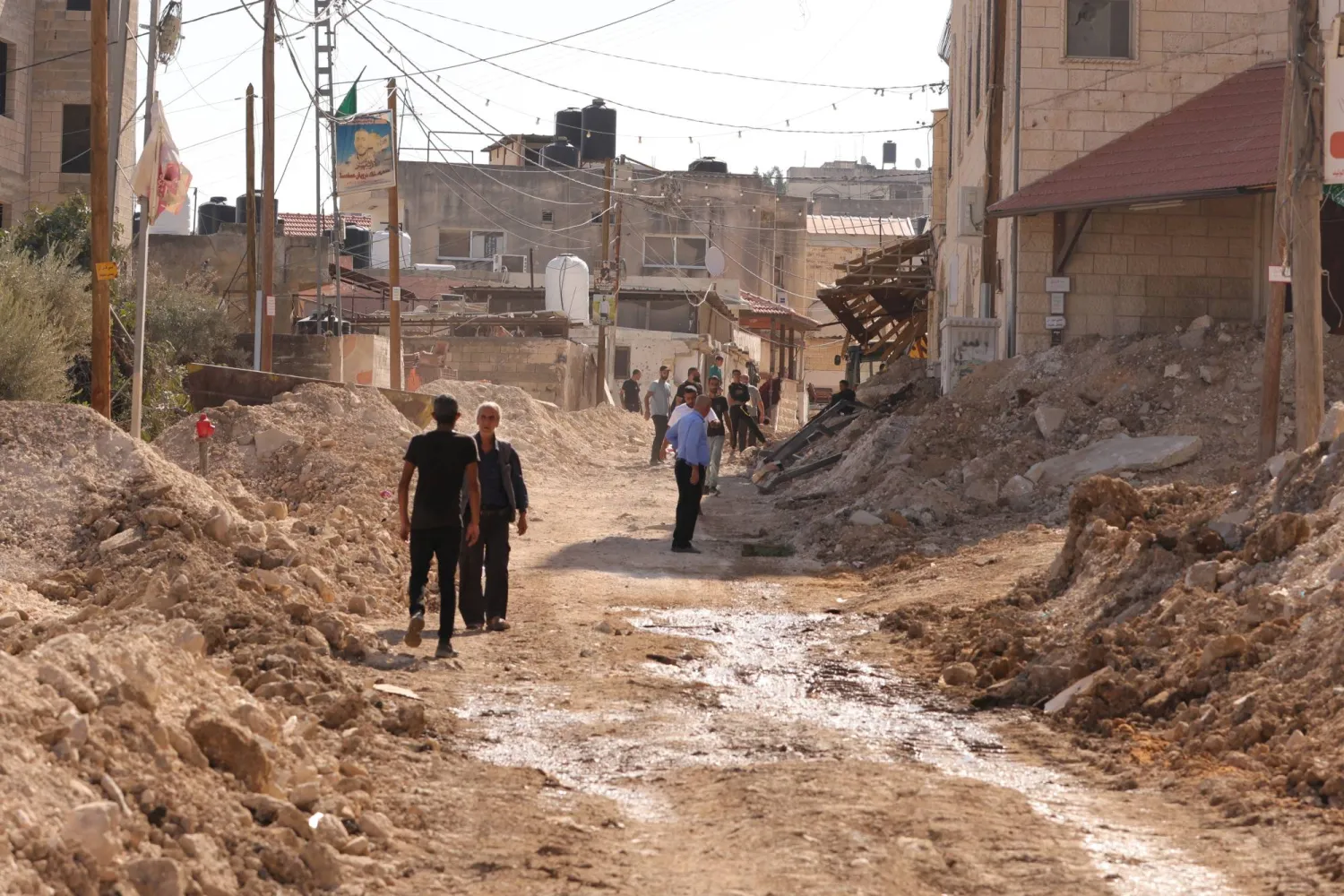 فلسطينيون يتفقدون الأضرار بعد يوم من الغارة الإسرائيلية على مدينة جنين بالضفة الغربية (إ.ب.أ)
