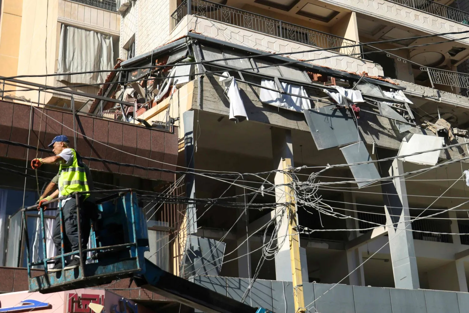 A worker is raised on a forklift at the site of an Israeli airstrike that targeted an apartment on al-Qaem street in Beirut's southern suburbs on September 26, 2024. (Photo by Ibrahim AMRO / AFP)