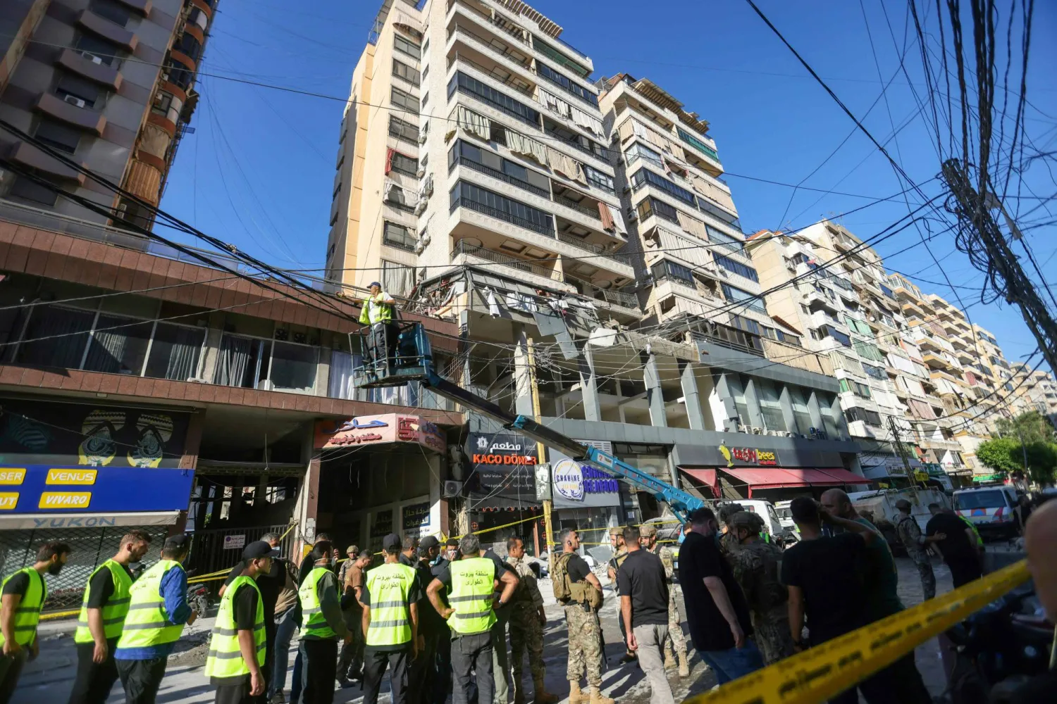 مواطنون ومسعفون بموقع استهداف إسرائيلي لقيادي في «حزب الله» بالضاحية الجنوبية لبيروت (أ.ف.ب)