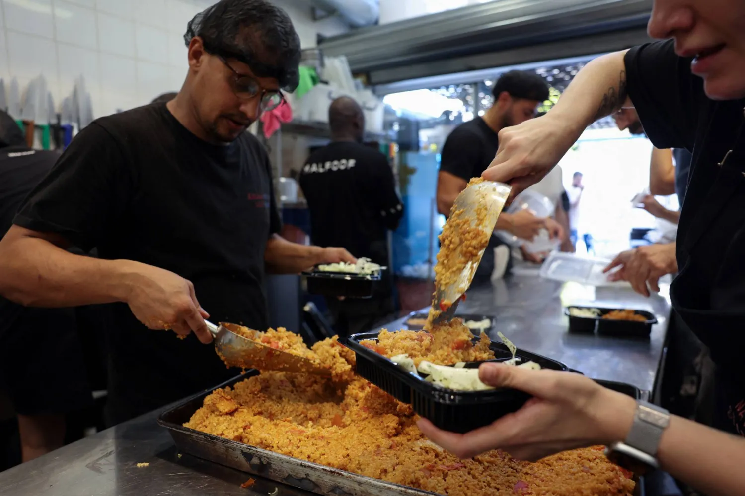 متطوعون في منظمة «نيشن ستيشن» غير الربحية يقومون بإعداد وجبات طعام لتوزيعها (رويترز)