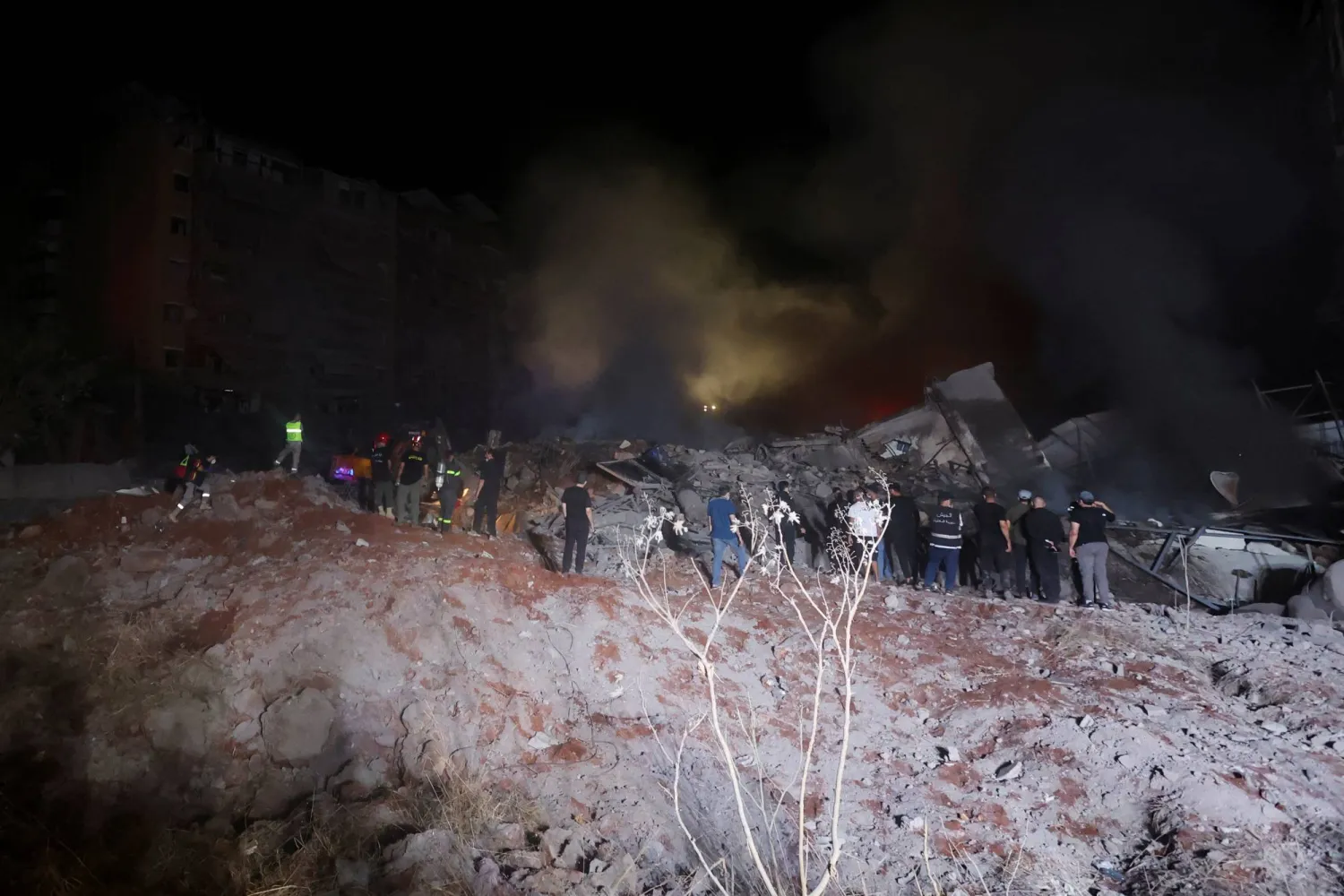 يتجمع الناس في موقع غارة إسرائيلية في الضاحية الجنوبية لبيروت (رويترز)