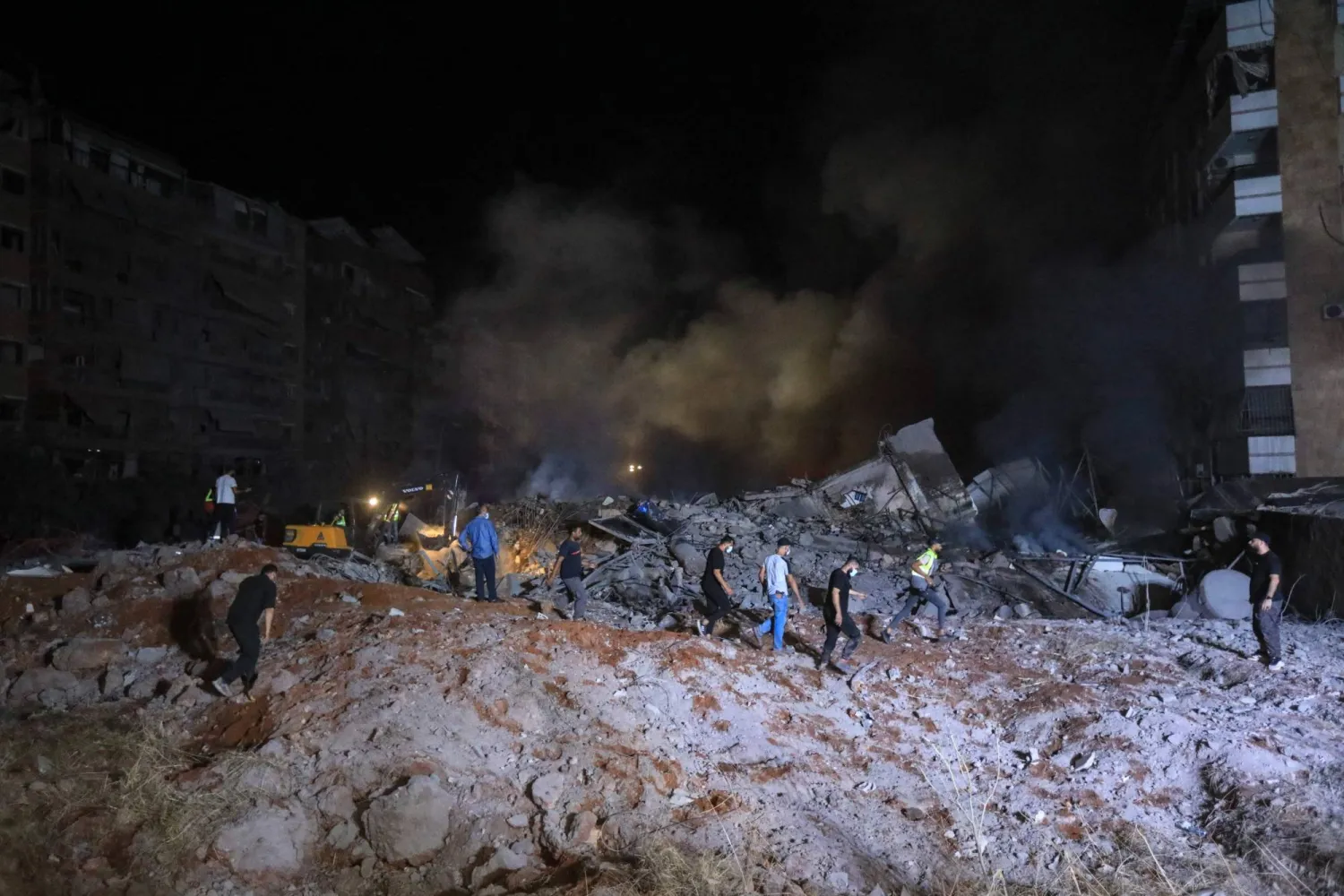 أشخاص ومُسعفون يقفون على أنقاض مبنى دمرته غارة إسرائيلية على الضاحية الجنوبية لبيروت (أ.ف.ب)