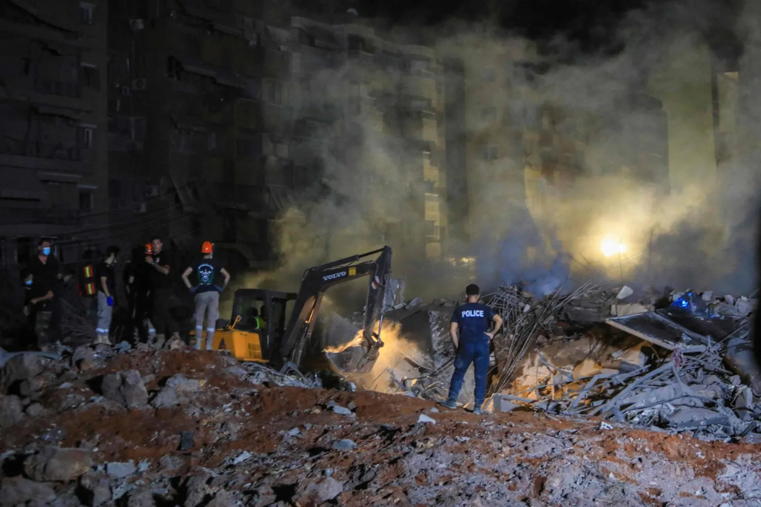 أشخاص يقفون على أنقاض مبنى دمرته الغارات الإسرائيلية على الضاحية الجنوبية لبيروت (أ.ف.ب)