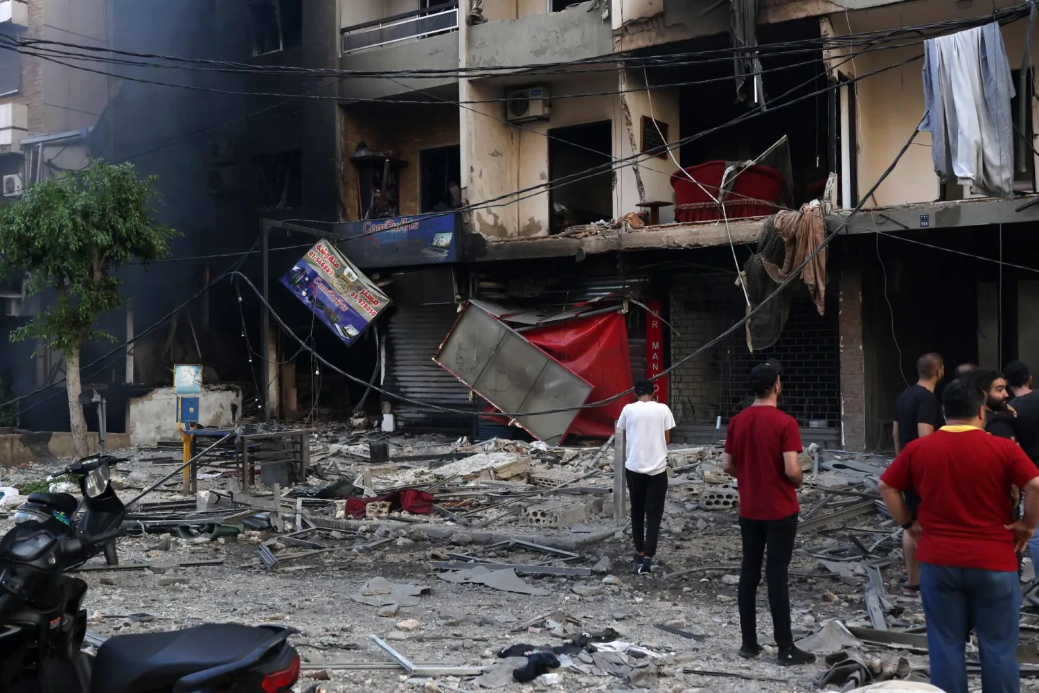 سكان يتفقدون الأضرار التي لحقت بالضاحية الجنوبية لبيروت نتيجة القصف الإسرائيلي الذي استمر طوال الليل (أ.ف.ب)