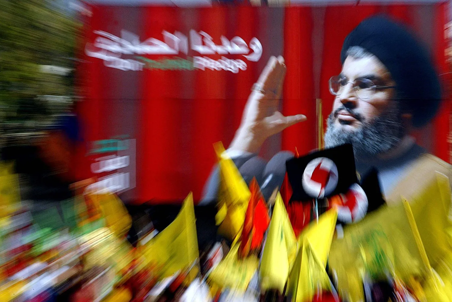 Hizbullah destekçileri, Beyrut'un güney banliyösünde Hasan Nasrallah'ın posterinin önünde bayrak sallıyor. (Arşiv - AFP)