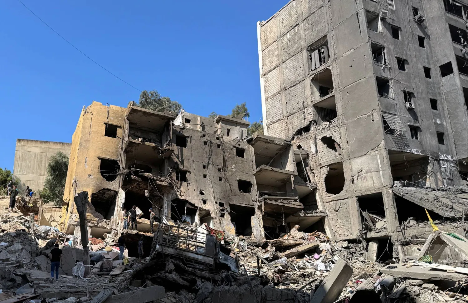 رجال يقفون في موقع الغارة الجوية الإسرائيلية التي قتلت حسن نصر الله في الضاحية الجنوبية لبيروت (رويترز)