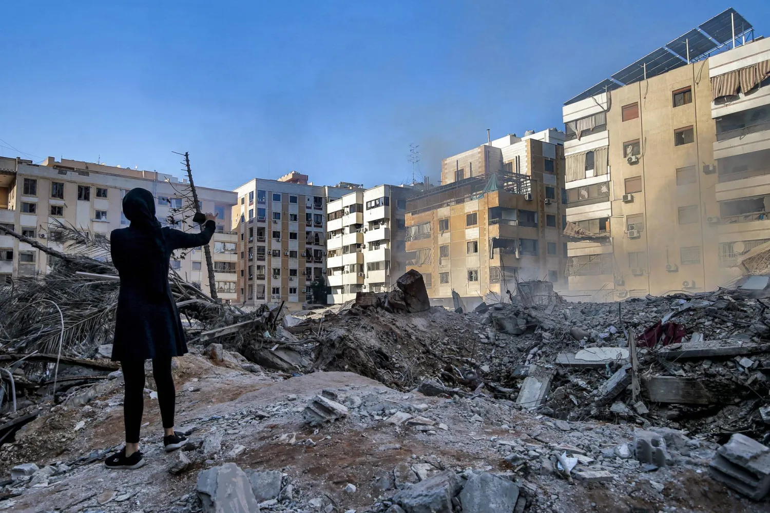 فتاة لبنانية تلتقط صوراً لمكان الغارة الإسرائيلية في الضاحية الجنوبية لبيروت (د.ب.أ)