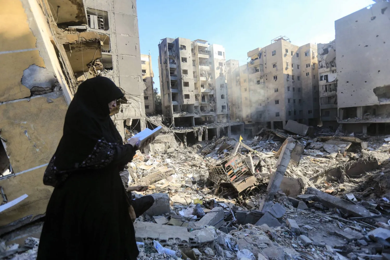 امرأة تقرأ القرآن على موقع اغتيال نصر الله بالضاحية الجنوبية لبيروت (أ.ف.ب)