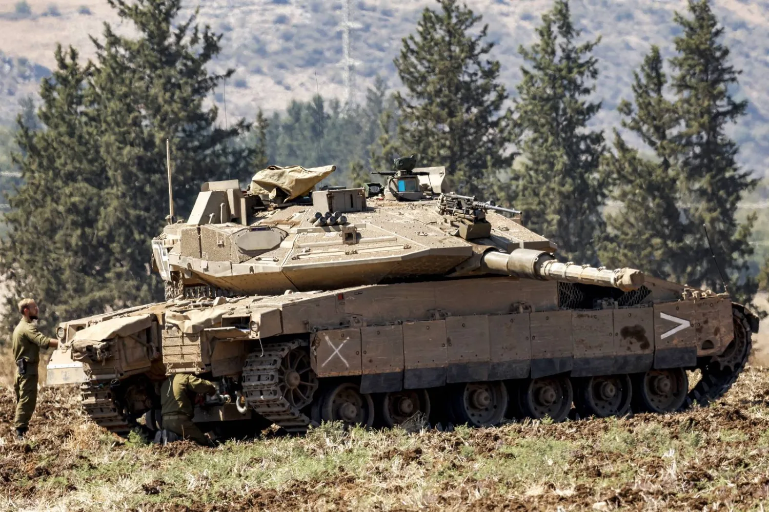 جندي من الجيش الإسرائيلي يقف بالقرب من دبابة قتال رئيسية منتشرة في شمال إسرائيل (أ.ف.ب)