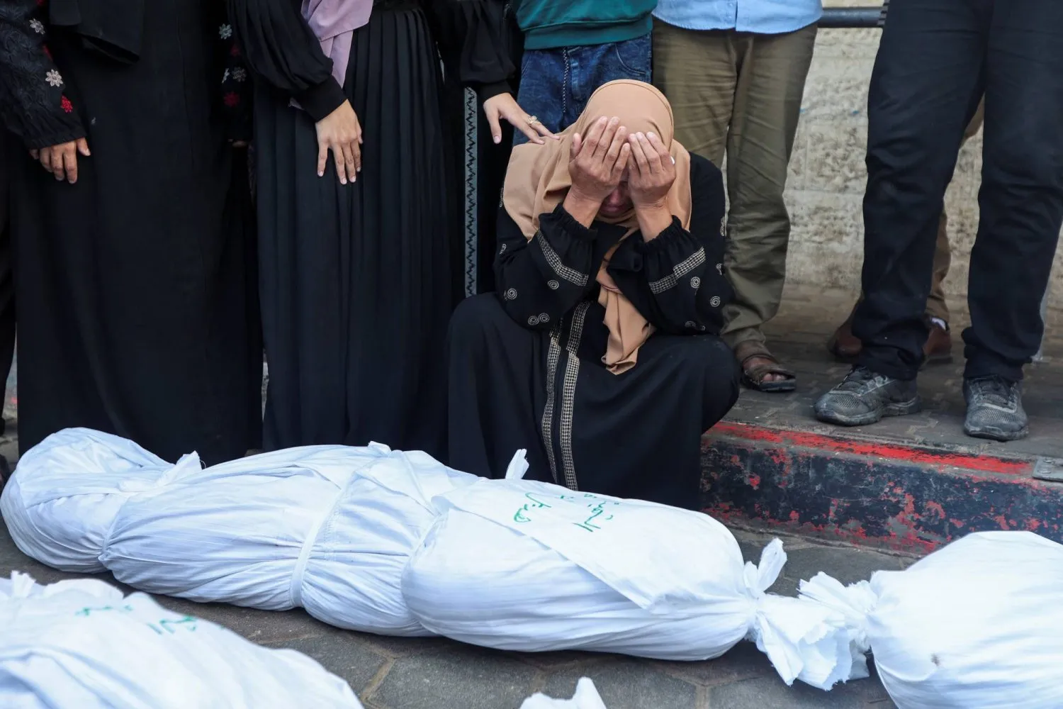 İsrail'in Deyr el Balah'taki Mescid-i Aksa Şehitleri Hastanesi'ne düzenlediği saldırıda öldürülen yakınlarının naaşlarının yanında bulunan Filistinliler (Arşiv - Reuters)