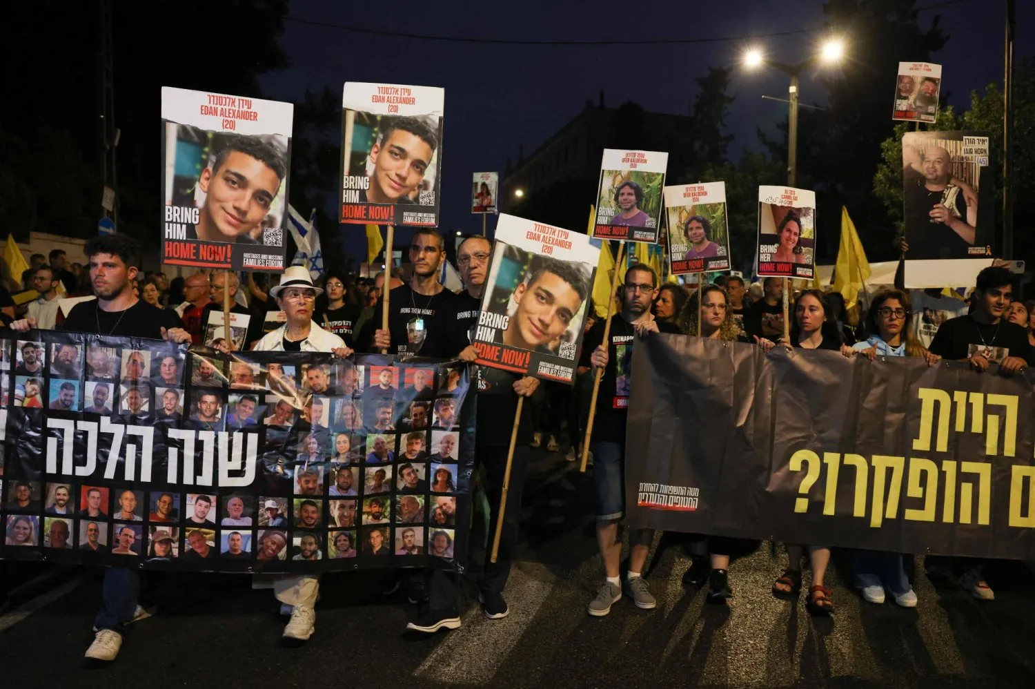 İsrailli rehinelerin yakınları Başbakan Binyamin Netanyahu'nun evinin önünde fotoğraflarını tutuyor (AFP)