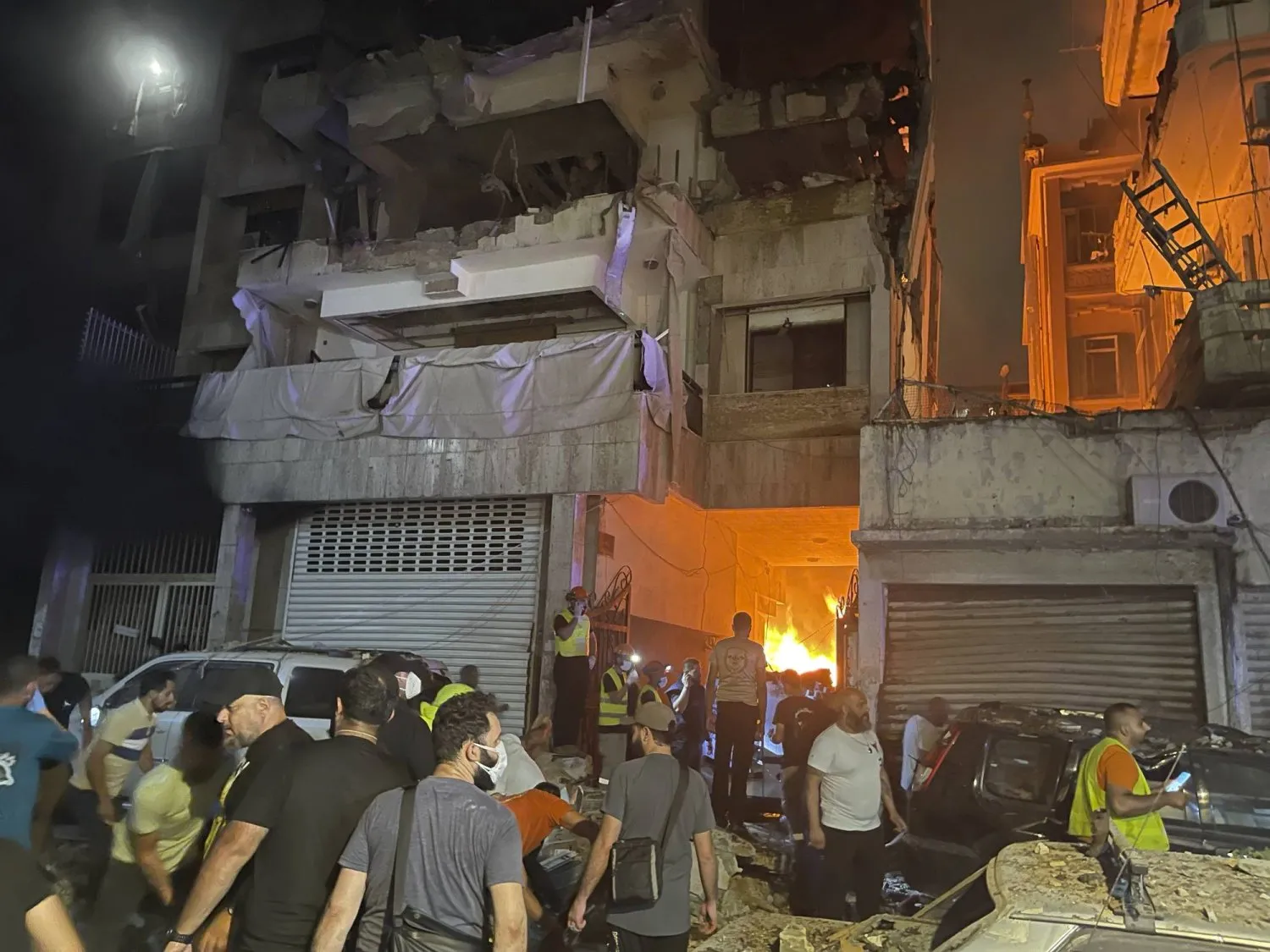 Beyrut şehir merkezinde İsrail'in dünkü hava saldırısında yıkılan binanın önünde toplanan kalabalık (AP)