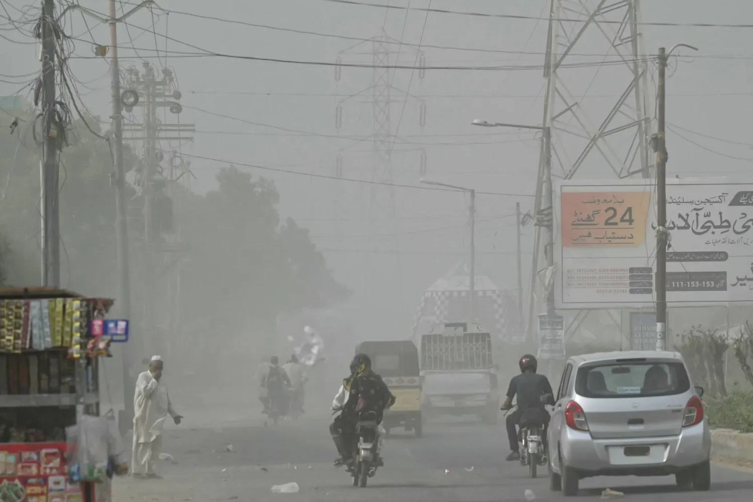 Commuters drive along a road amid a dust storm in Karachi on October 10, 2024. (Photo by Asif HASSAN / AFP)