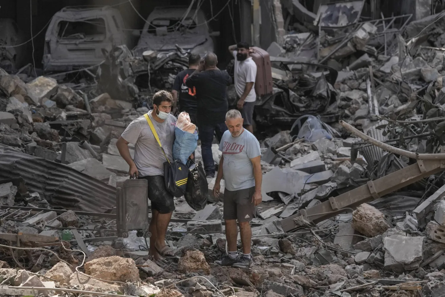 سكان لبنانيون يسيرون وسط حطام مبنى تعرض لغارة إسرائيلية في بيروت (أ.ب)