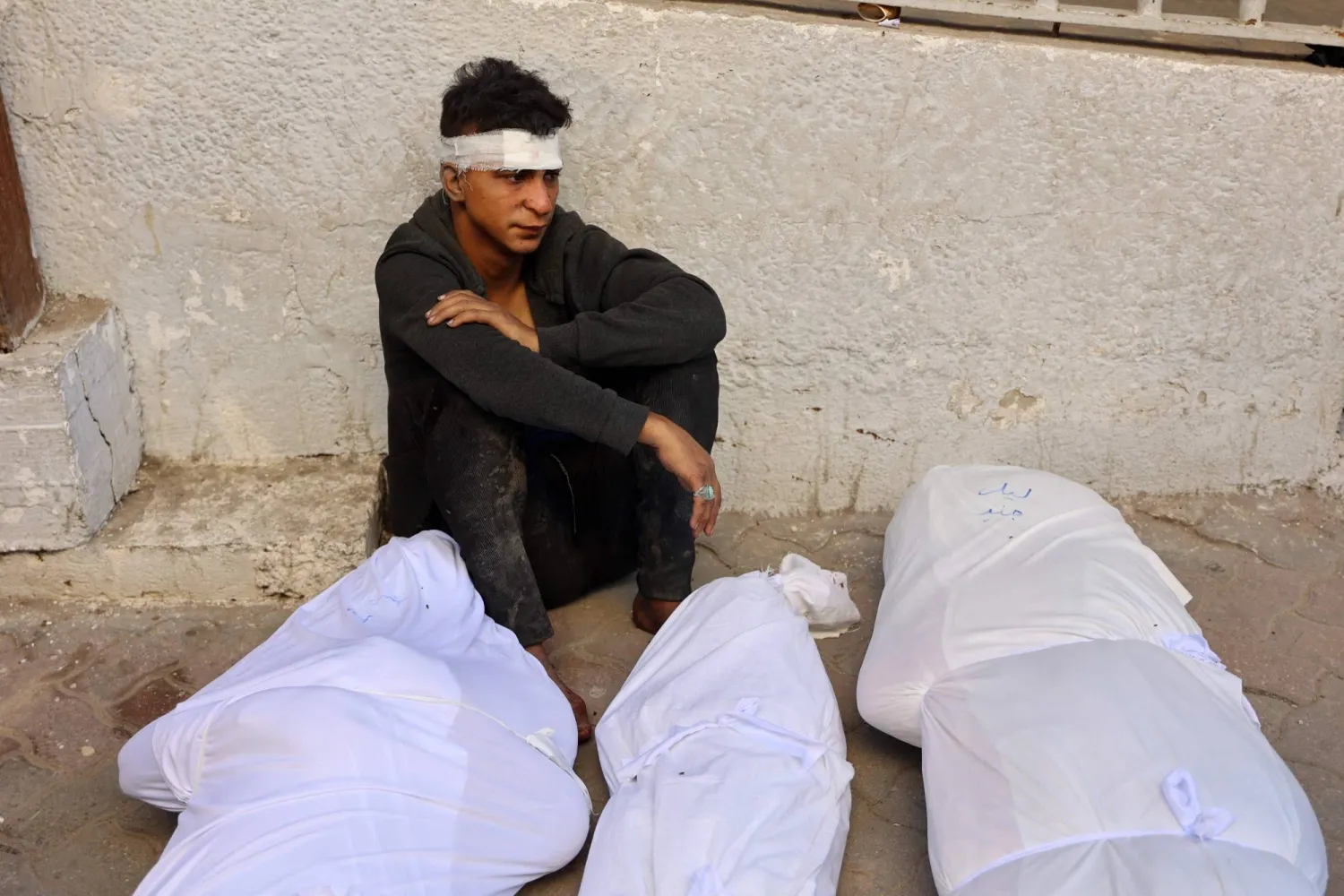 شاب مصاب بجوار جثث أقاربه الذين قتلوا في غارة جوية إسرائيلية ليلية في مخيم جباليا للاجئين في شمال قطاع غزة، 12 أكتوبر 2024 (أ.ف.ب)