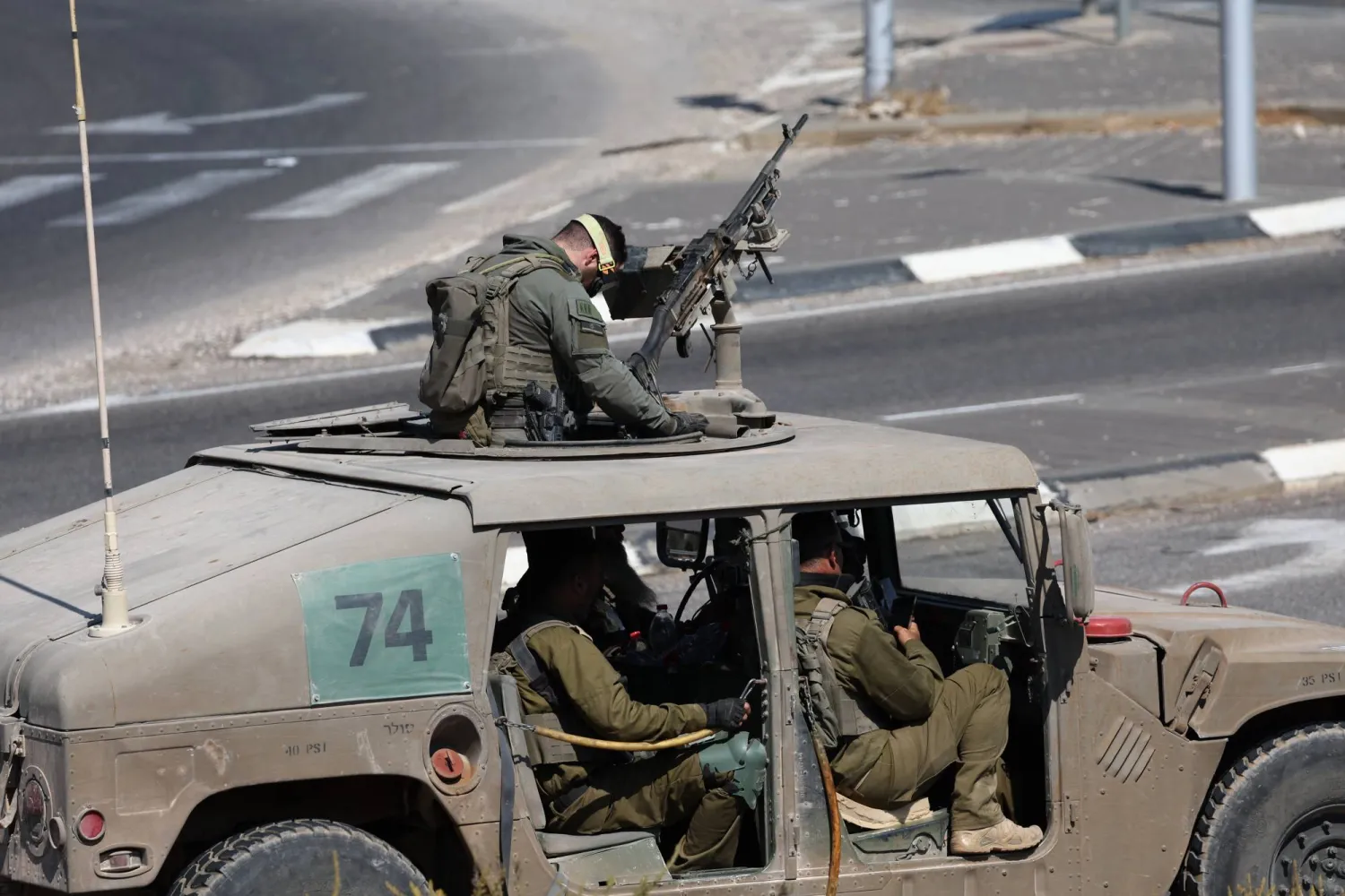 جندي إسرائيلي يمسك بمدفع رشاش على سطح آلية عسكرية على الحدود مع لبنان (إ.ب.أ)