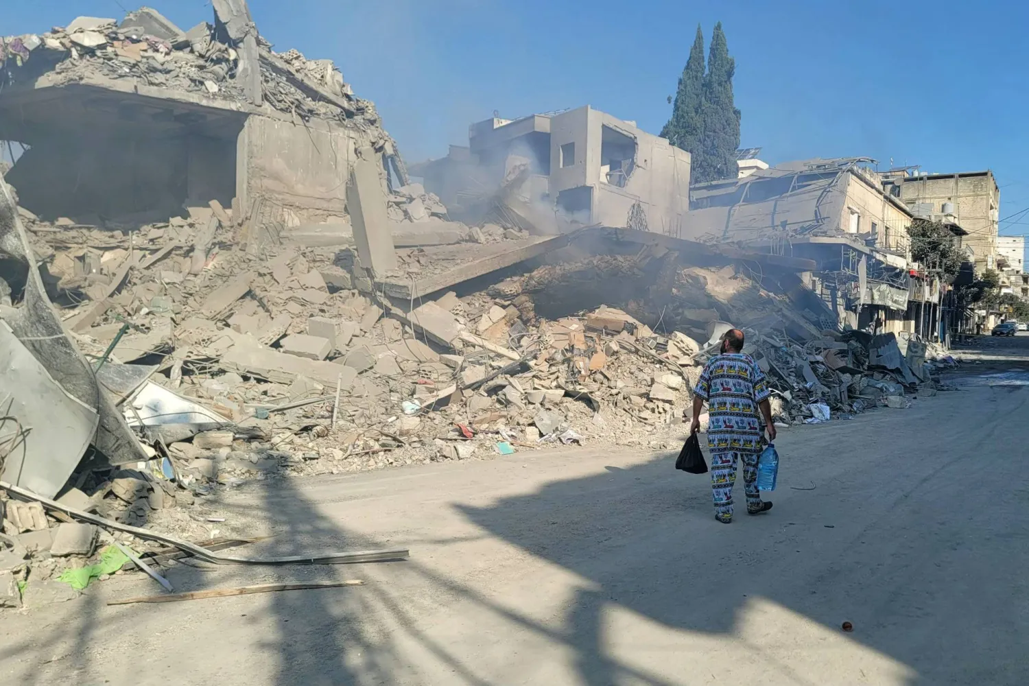 رجل يسير بجوار أنقاض محال تجارية قديمة دُمّرت جراء غارات إسرائيلية على النبطية جنوب لبنان (أ.ف.ب)