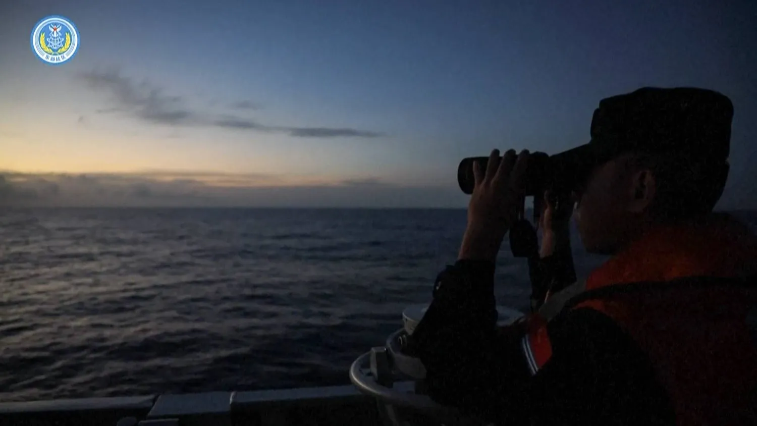 Çin ordusu tarafından paylaşılan bir videoda askeri gemide dürbünle ufka bakan bir subay görülüyor. (Çin Ordusu)