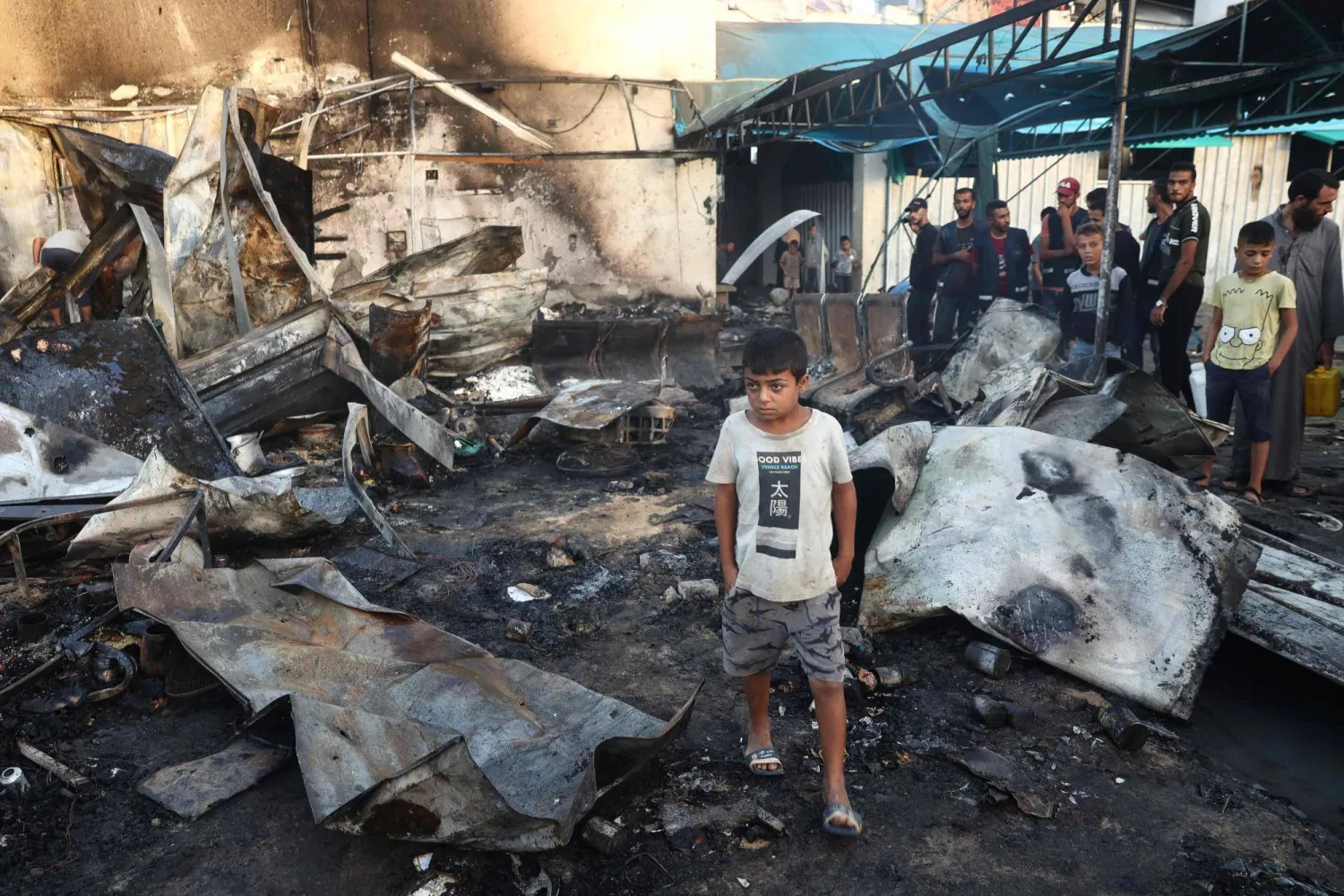 طفل فلسطيني يمشي بينما يتفقد الناس الدمار الذي أعقب غارة للجيش الإسرائيلي حول خيام النازحين داخل أسوار «مستشفى شهداء الأقصى» (أ.ف.ب)