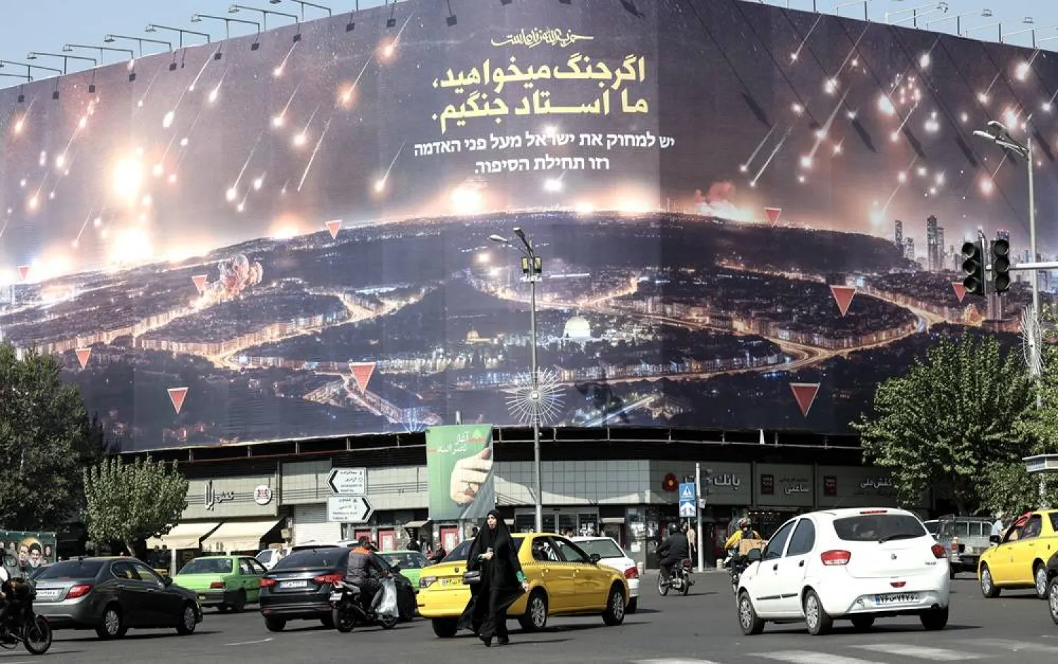 People pass by an anti-Israel billboard depicting Iran's missile attack on Israel with a sentence reading in Persian “If you want war, we are the master of war”, at the Enqelab Square, in Tehran, Iran, 07 October 2024. (EPA) 