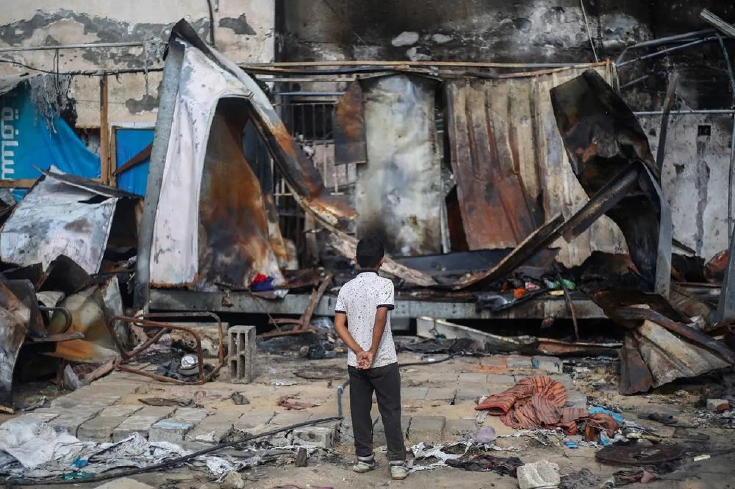 A Palestinian boy looks at destroyed shelters at the site of an Israeli airstrike which hit tents for displaced people two days earlier in the courtyard of Al-Aqsa Martyrs Hospital in Deir al-Balah in the central Gaza Strip on October 16, 2024. (AFP)
