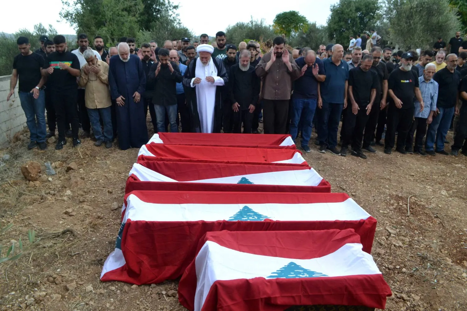 مشيعون يشاركون بتشييع 23 نازحاً لبنانياً قُتلوا بغارة إسرائيالية في بلدة إيطو بالشمال (أ.ف.ب)