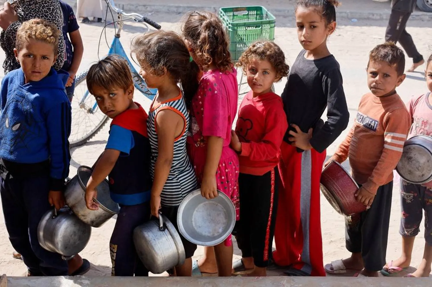  Palestinian children queue to receive food cooked by a charity kitchen, amid the Israel-Hamas conflict, in Khan Younis in the southern Gaza Strip, October 16, 2024. (Reuters)