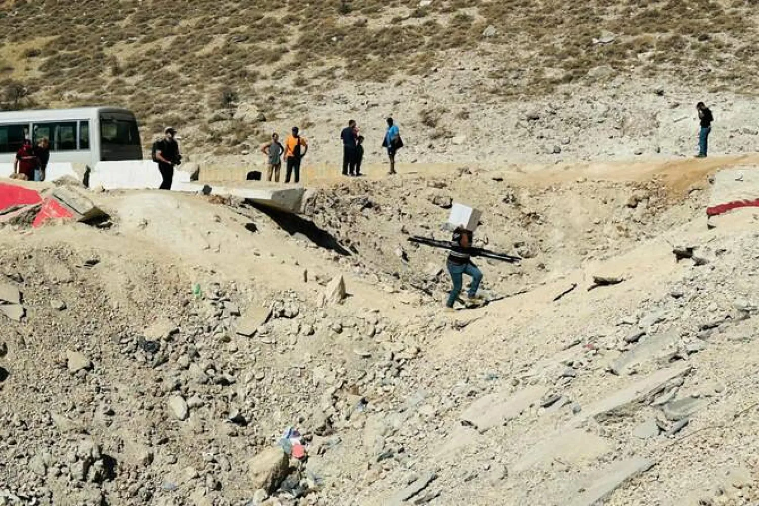 People fleeing Israeli bombardment in Lebanon walk across a crater caused by an Israeli strike, in the area of Masnaa on the Lebanese side of the border crossing with Syria, on October 15, 2024. Syrian state media said Israeli jets also targeted Latakia province early Thursday. (AFP)
