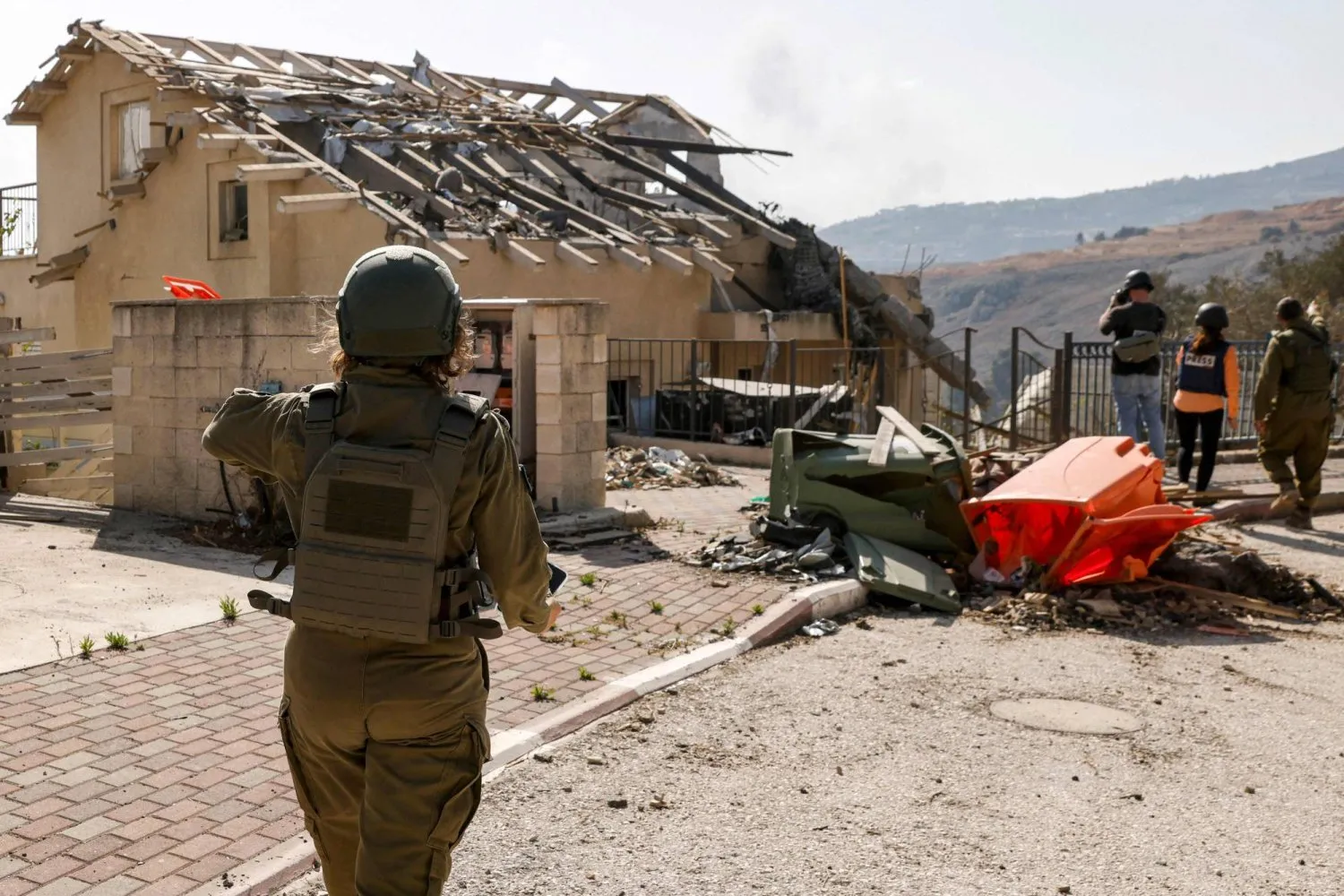  İsrail'in kuzeyindeki Metulla'da Hizbullah füzeleri tarafından hasar gören bir evin yakınındaki İsrail askeri (AFP)