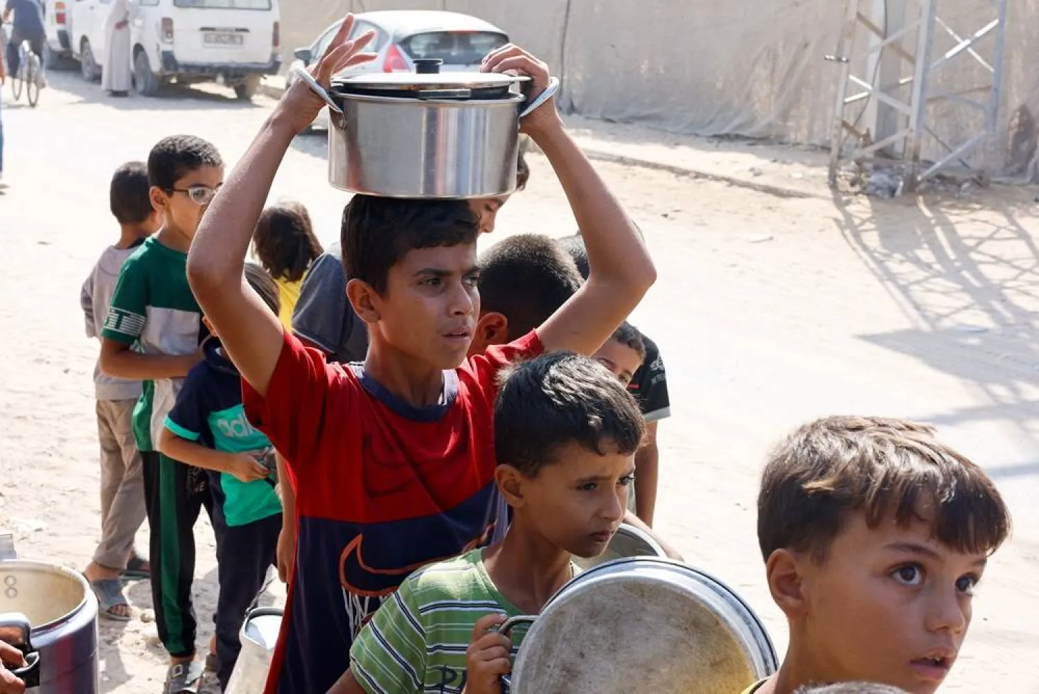 Palestinian children queue to receive food cooked by a charity kitchen, amid the Israel-Hamas conflict, in Khan Younis in the southern Gaza Strip, October 16, 2024. (Reuters) 