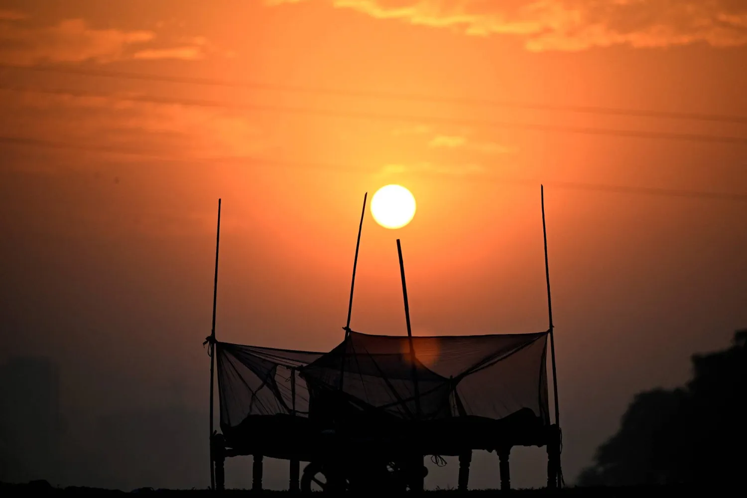 People sleep inside a mosquito net on the banks of river Yamuna in New Delhi on October 17, 2024. (Photo by SAJJAD HUSSAIN / AFP)