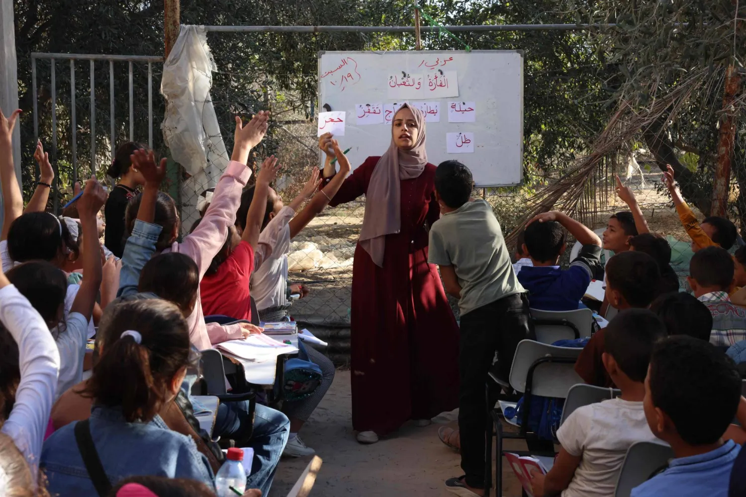 معلمة تقف في خان يونس بين طلابها الذي حضروا إلى المدرسة المؤقتة (أ.ف.ب)
