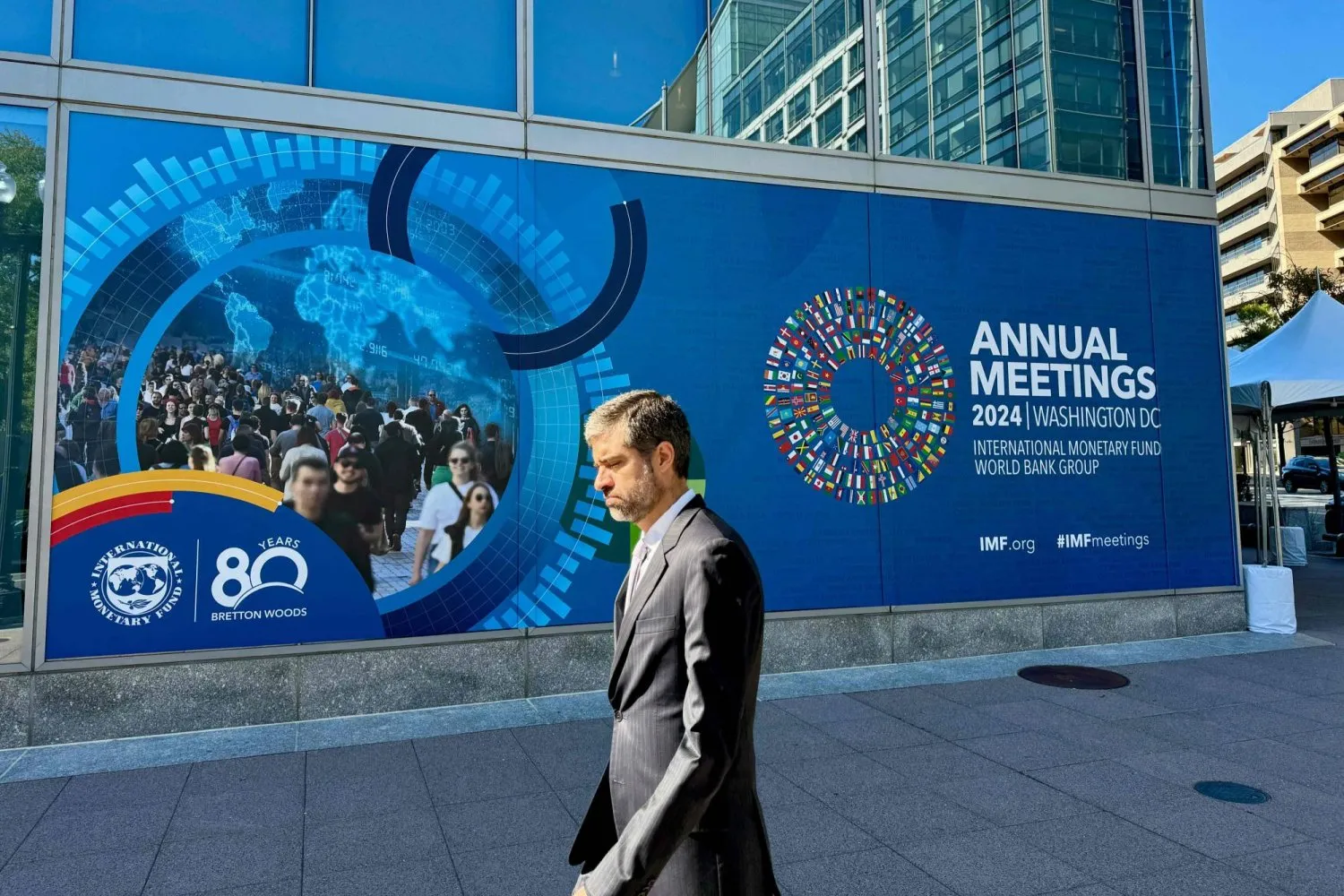 A man walks in front of banners for the 2024 autumn Annual Meetings outside the headquarters of the IMF in Washington (AFP)

 
