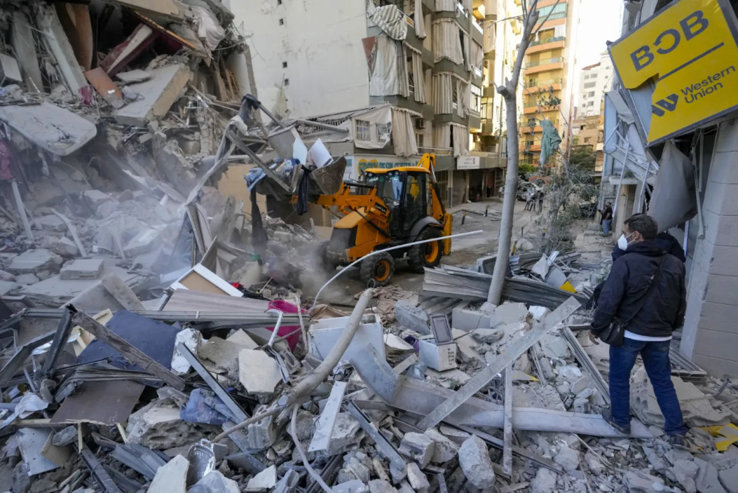 Rescue workers use a bulldozer to remove rubble of destroyed buildings a the site of an Israeli airstrike on Sunday night that hit several branches of the Hezbollah-run al-Qard al-Hassan in Beirut's southern suburb, Lebanon, Monday, Oct. 21, 2024. (AP Photo/Hassan Ammar)